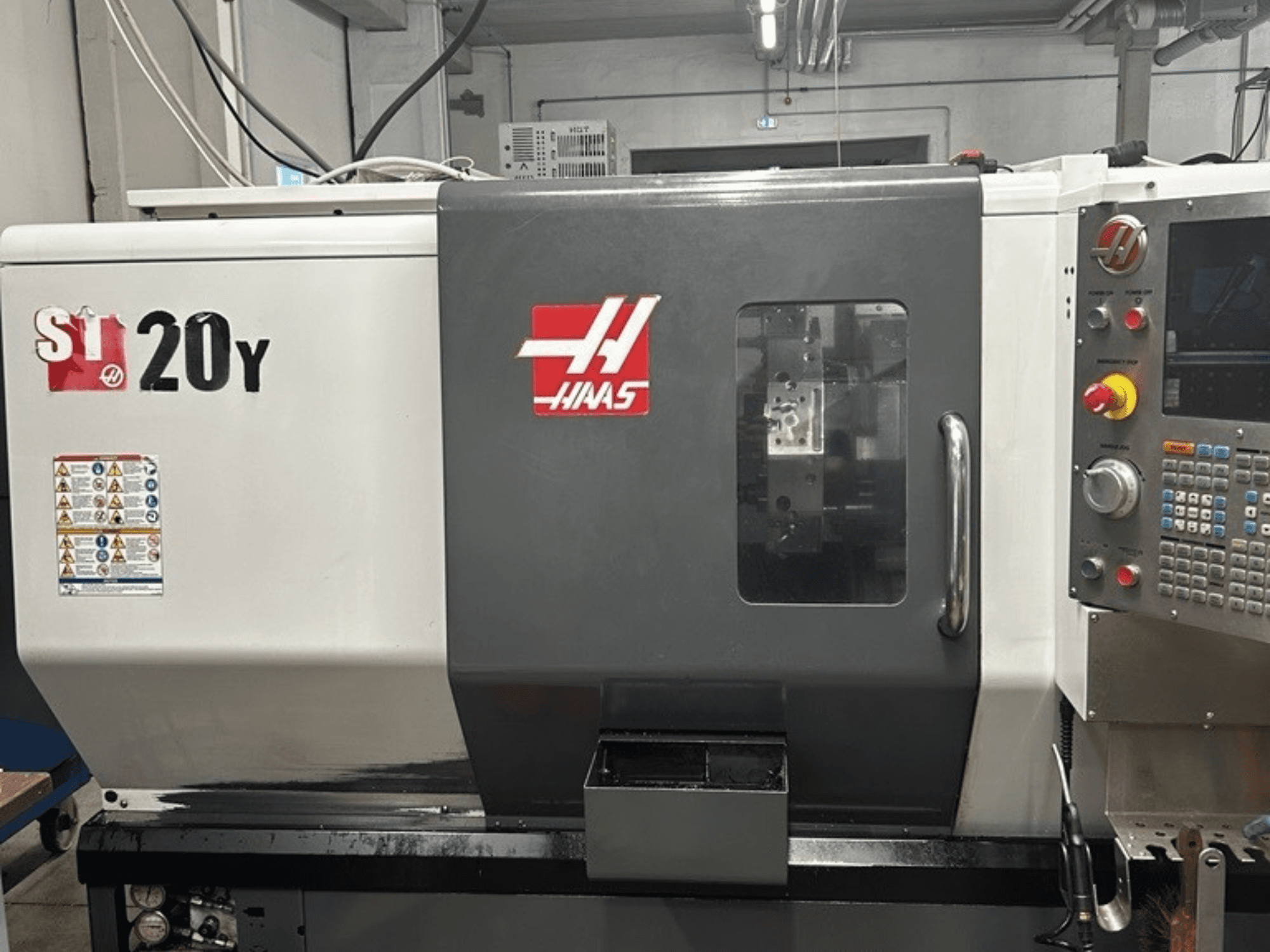 Haas ST-20Y CNC lathe, front view, showing control panel, safety labels, and operational window.