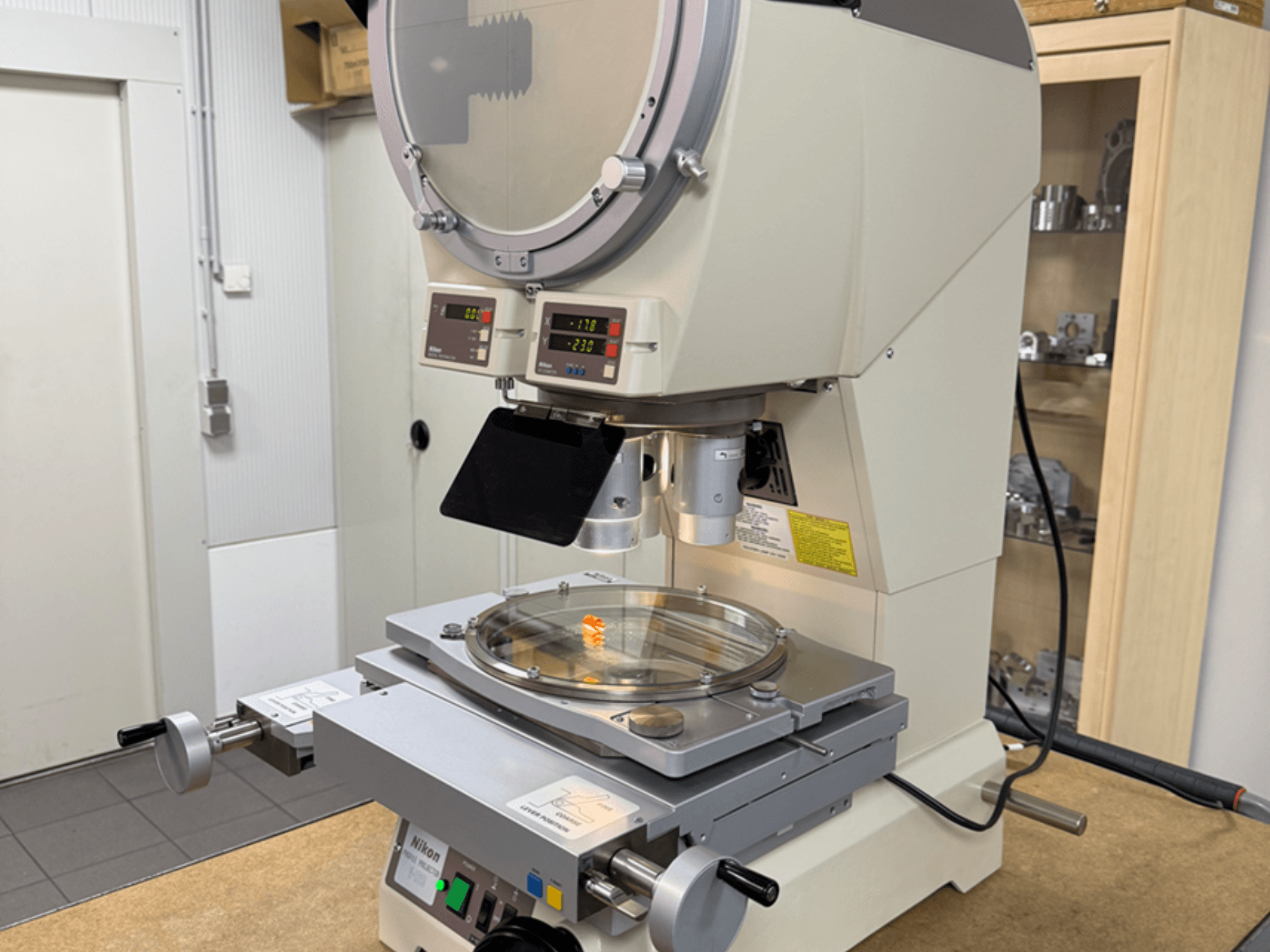 Nikon model microscope from a front view, featuring digital displays, an adjustable stage, and a circular glass plate.