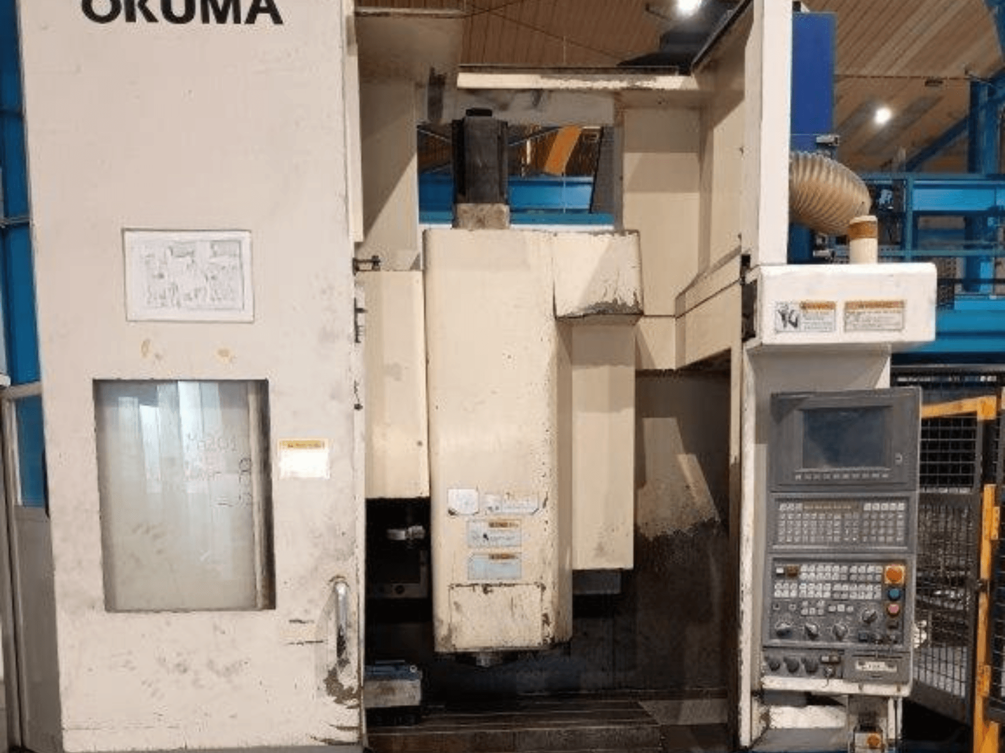 Okuma CNC milling machine, front view, features control panel with buttons, display, and visible marks on the machine body.