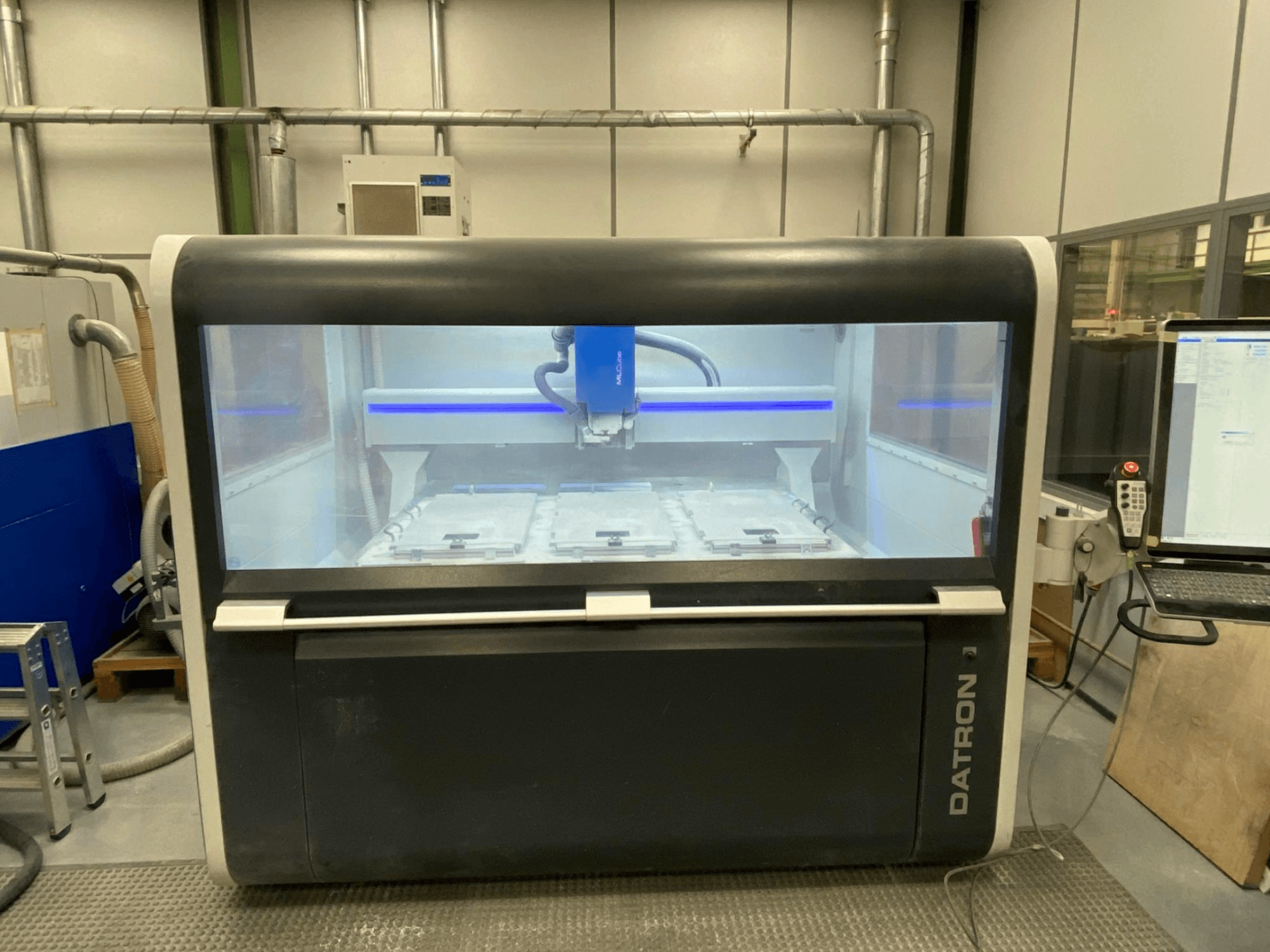 Datron MLCube B Vertical Machining Centre front view, showcasing control panel, workspace, and cutting head inside glass enclosure.