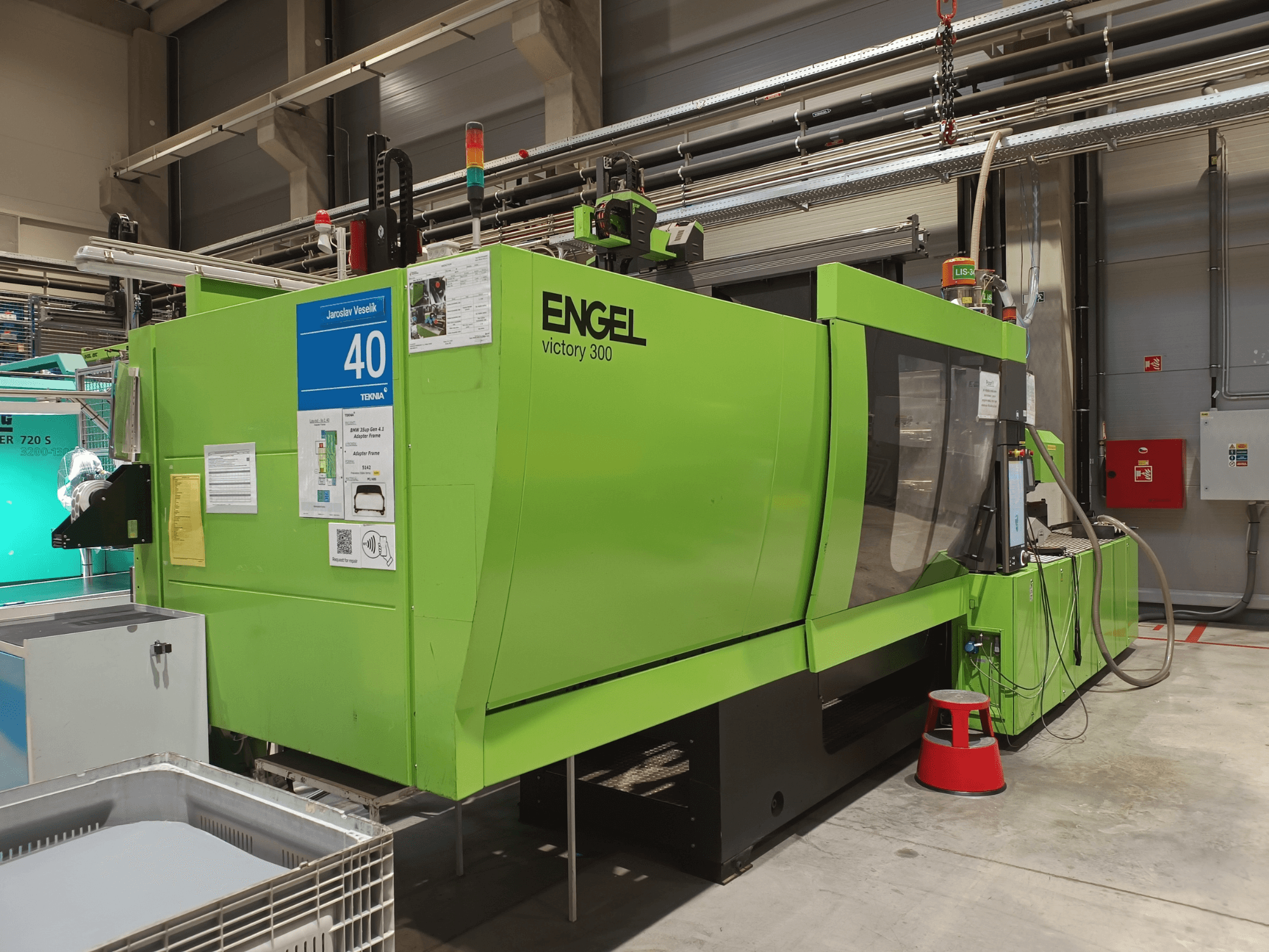 Green ENGEL Victory 300 injection molding machine, side view, with control panel and safety signage visible in a production area.