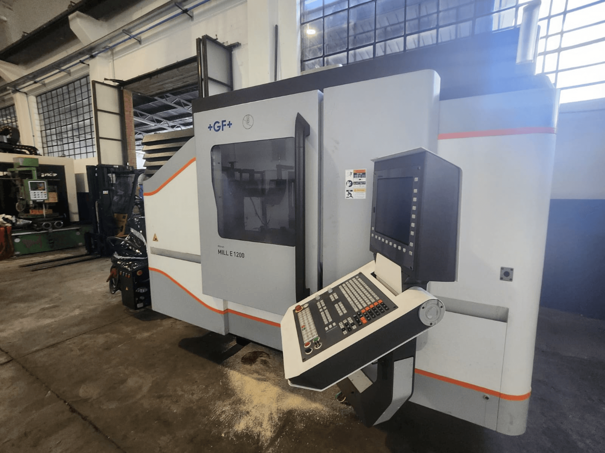 GF MILL E1200, front view of milling machine with control panel, display screen, and safety labels, in workshop setting.