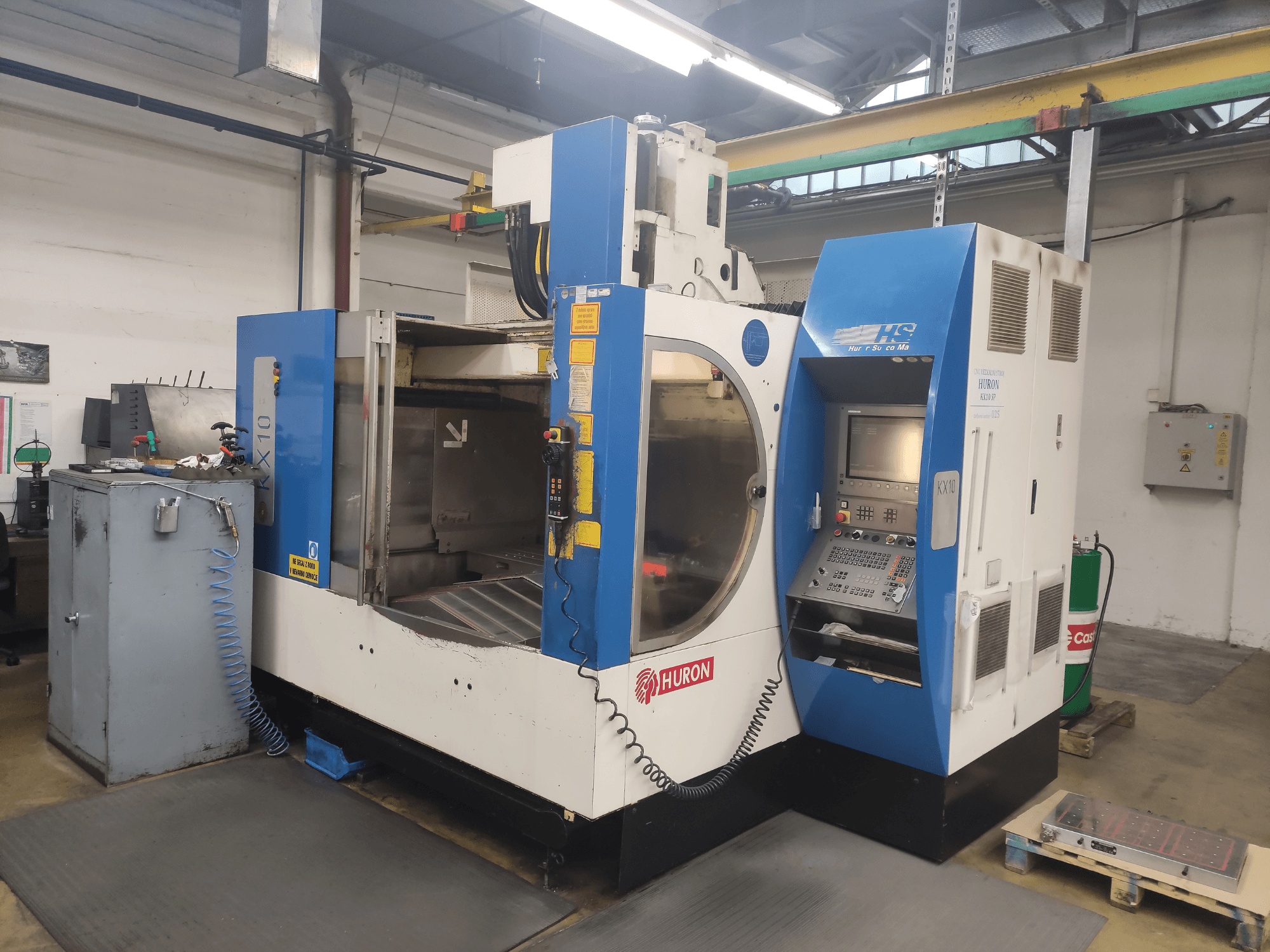 HURON KX10 CNC machine in a workshop, front view, featuring control panel and large opening for machining.