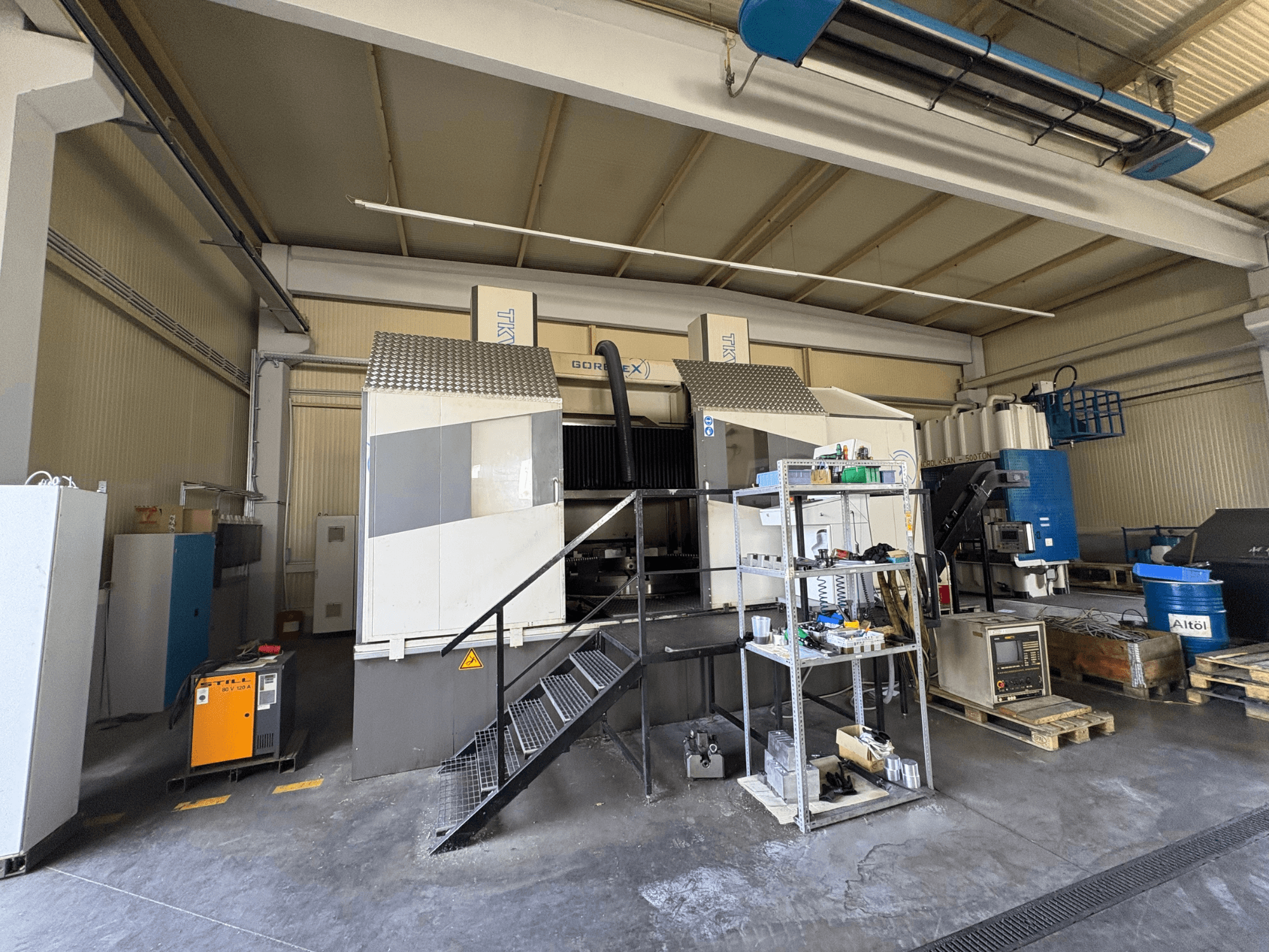 Industrial machining setup with GORAT X machine, side view; includes tools, control panel, and equipment on shelves.