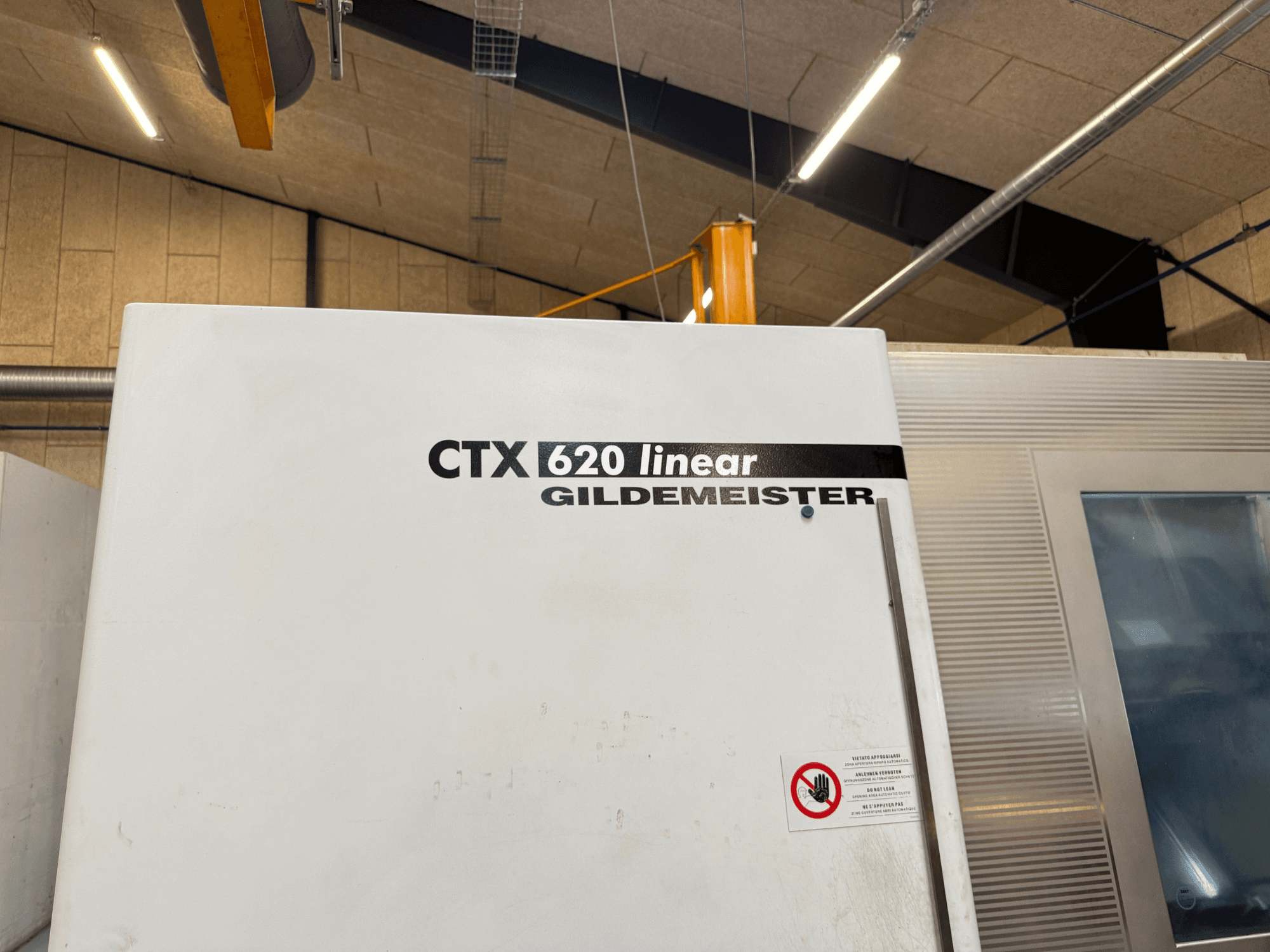 CTX 620 Linear Gildemeister machine side view, featuring a white exterior and safety warning labels.