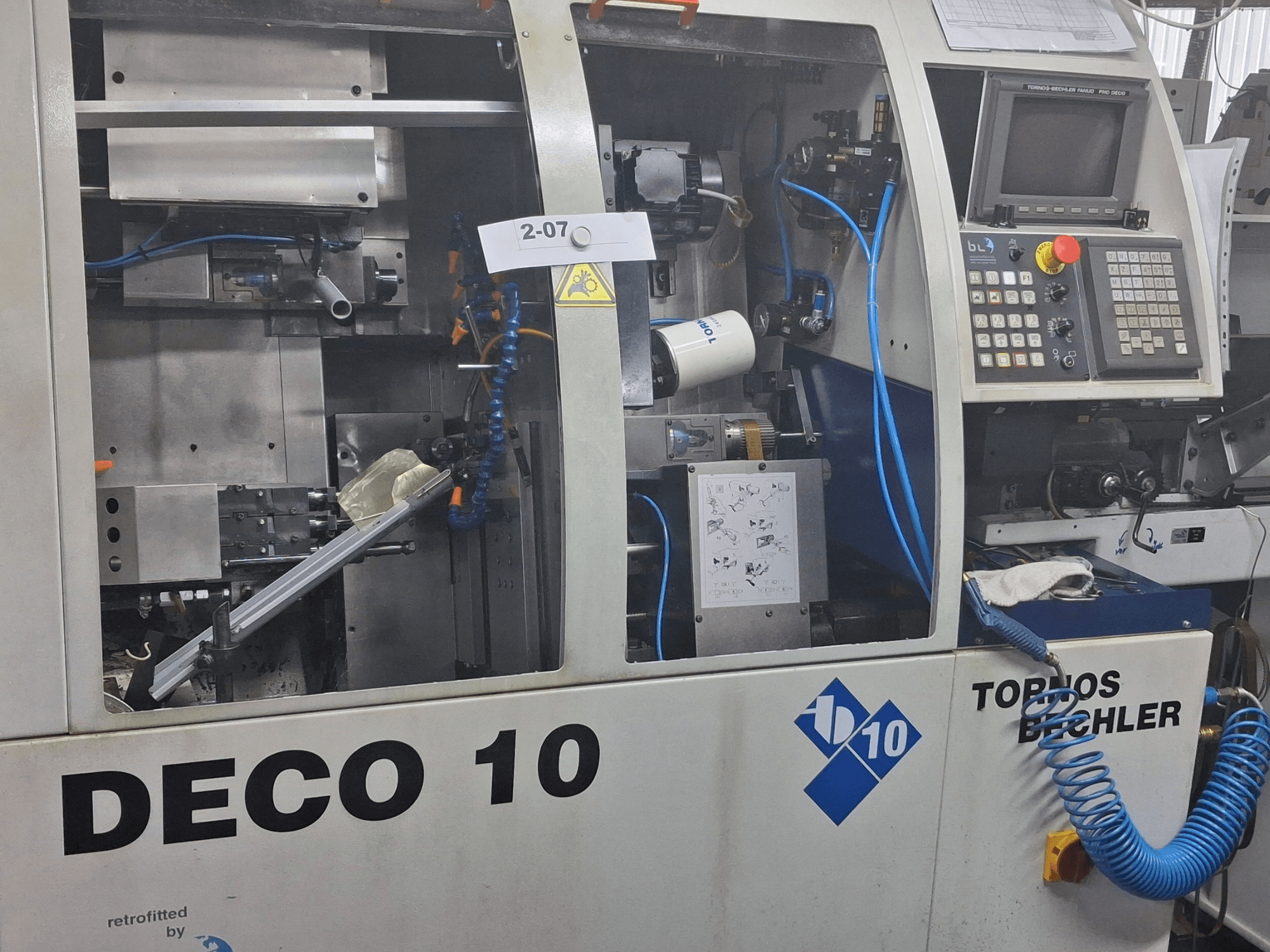 Close-up view of TORNOS Deco 10a Swiss Type Turning Machine, showcasing internal mechanism and control panel details.