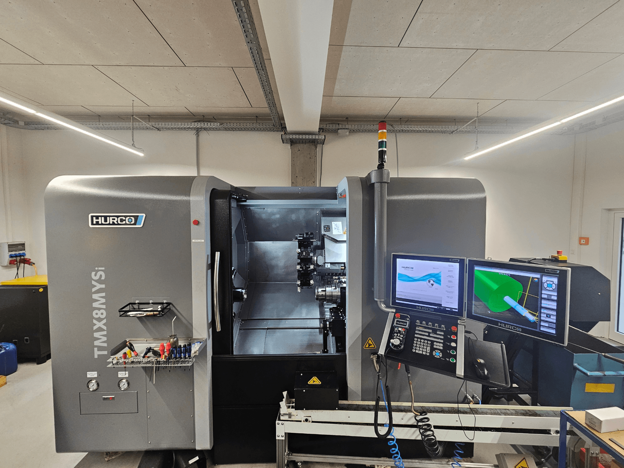 Hurco TMX 8 MYSi turn-mill centre in a workshop, featuring dual monitors, control panel, and tools on the side.