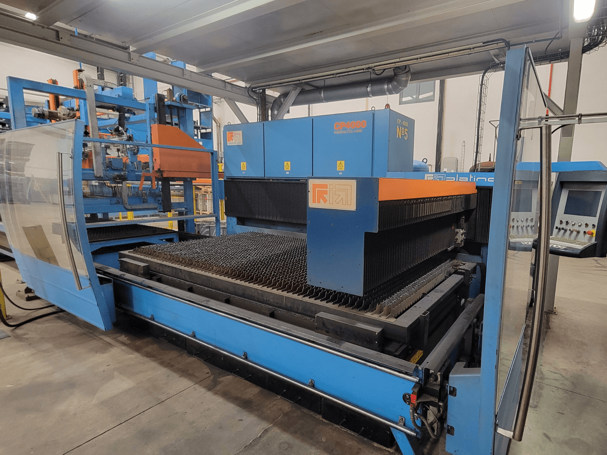 RIK CP4060 laser cutting machine in blue, side view showing metal cutting grid and control panel. Ideal for industrial applications.