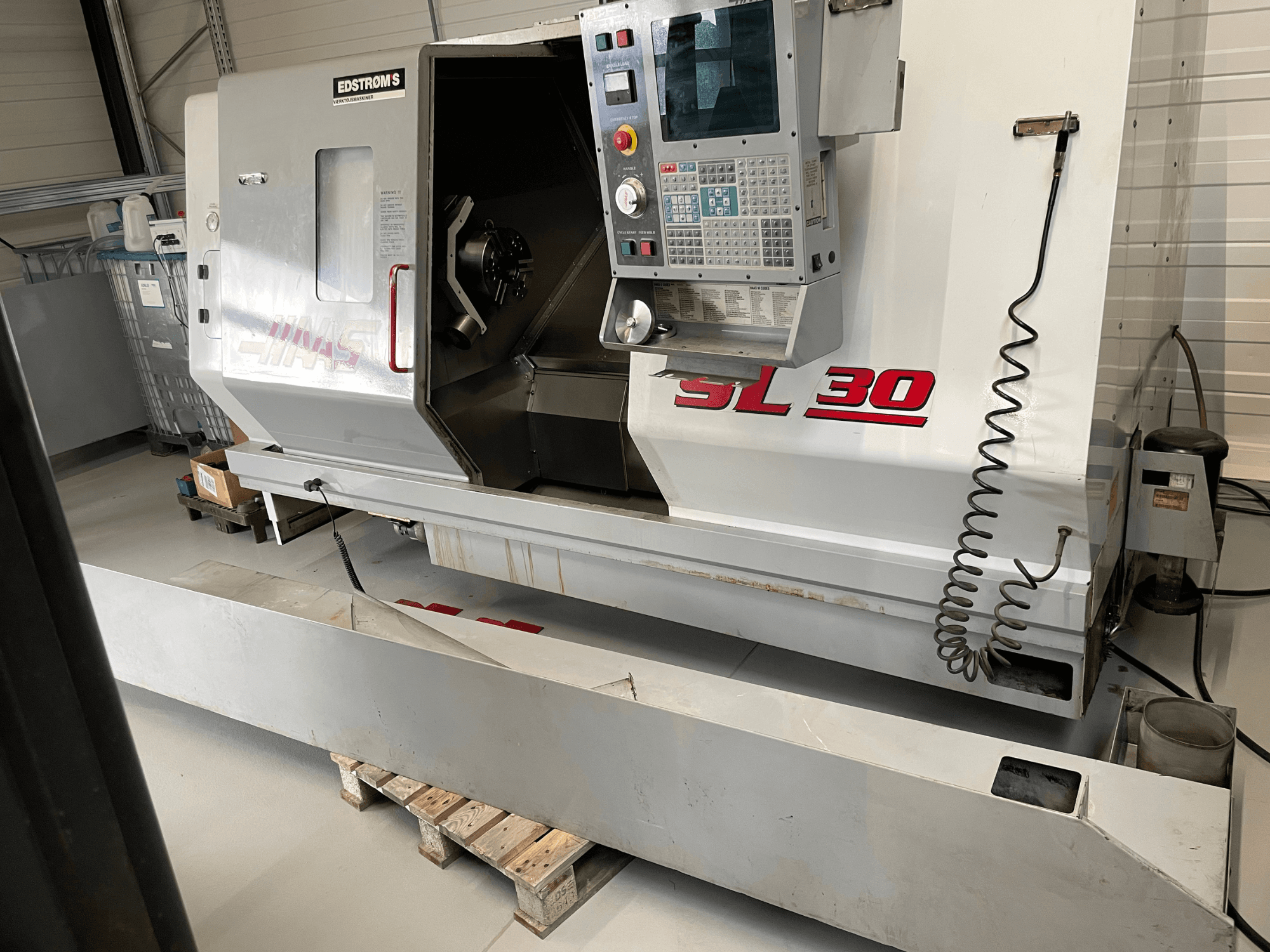 Haas SL 30 CNC lathe machine in a workshop, side view, featuring control panel and open spindle for machining tasks.