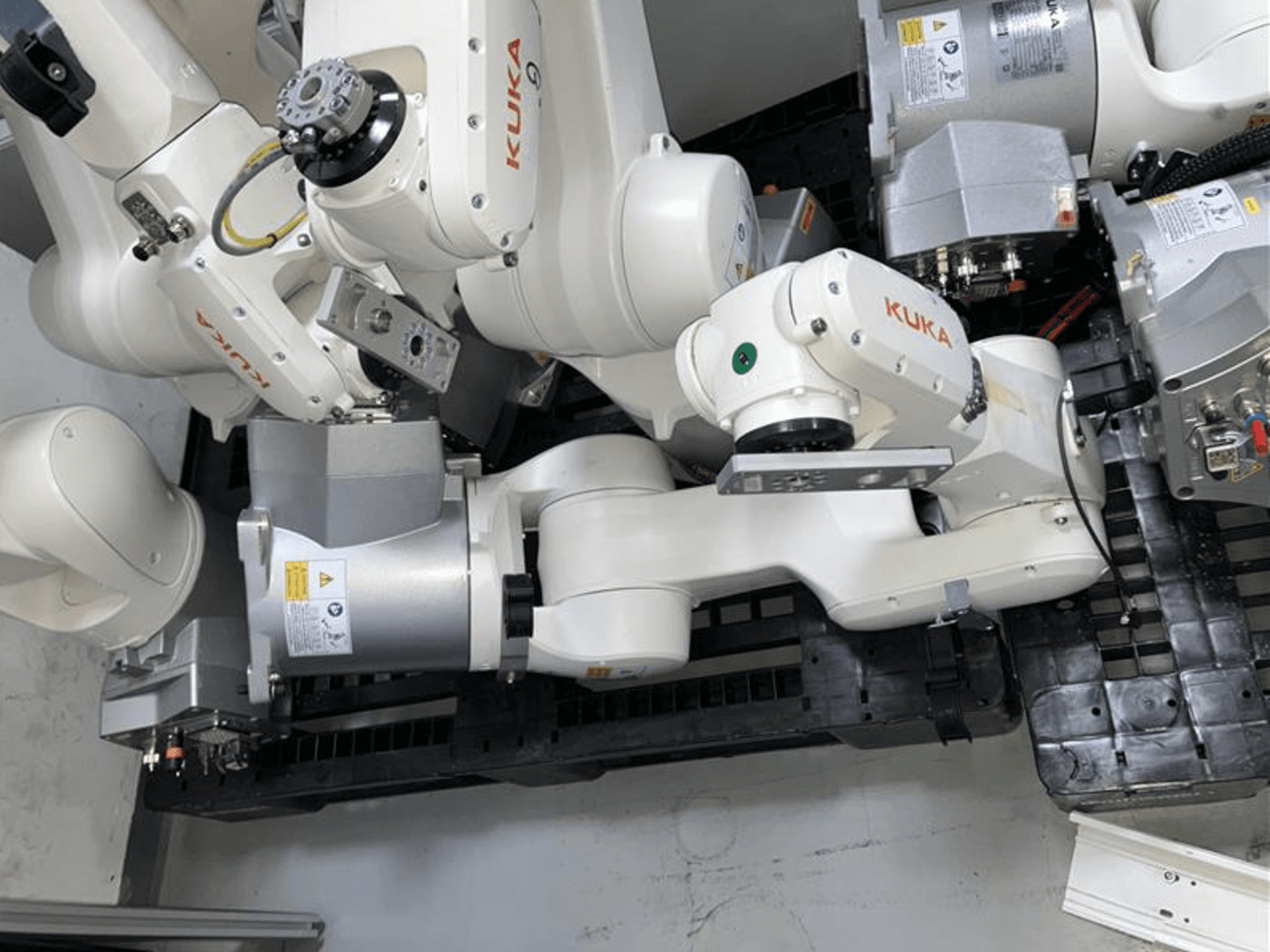 KUKA KR 6 R900 CR robot arm in a top view, featuring multiple joints and motors, fitted on a black base with cables.