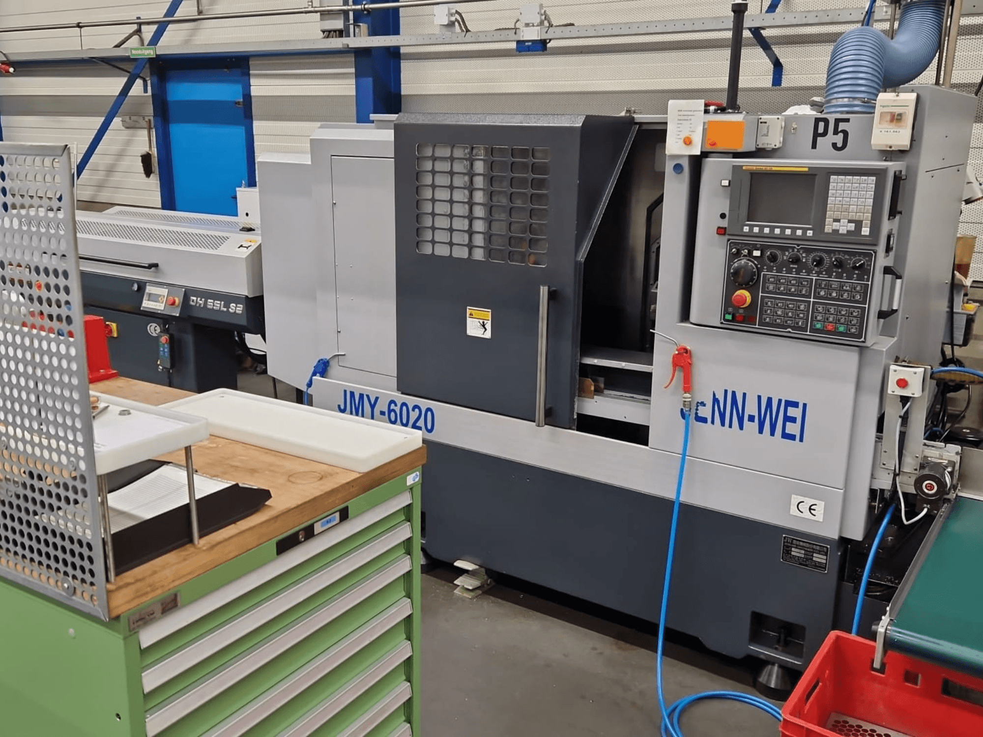 CNC lathe machine, model JMY-6020 by cNN-WEI, viewed from the front. Features control panel, emergency stop, and coolant line.