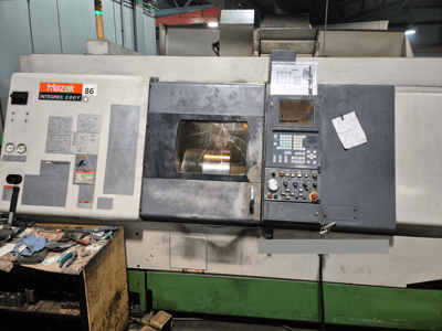 Mazak Integrex 200Y lathe machine, front view, with control panel and tools on a bench. Visible gauges and display screen.