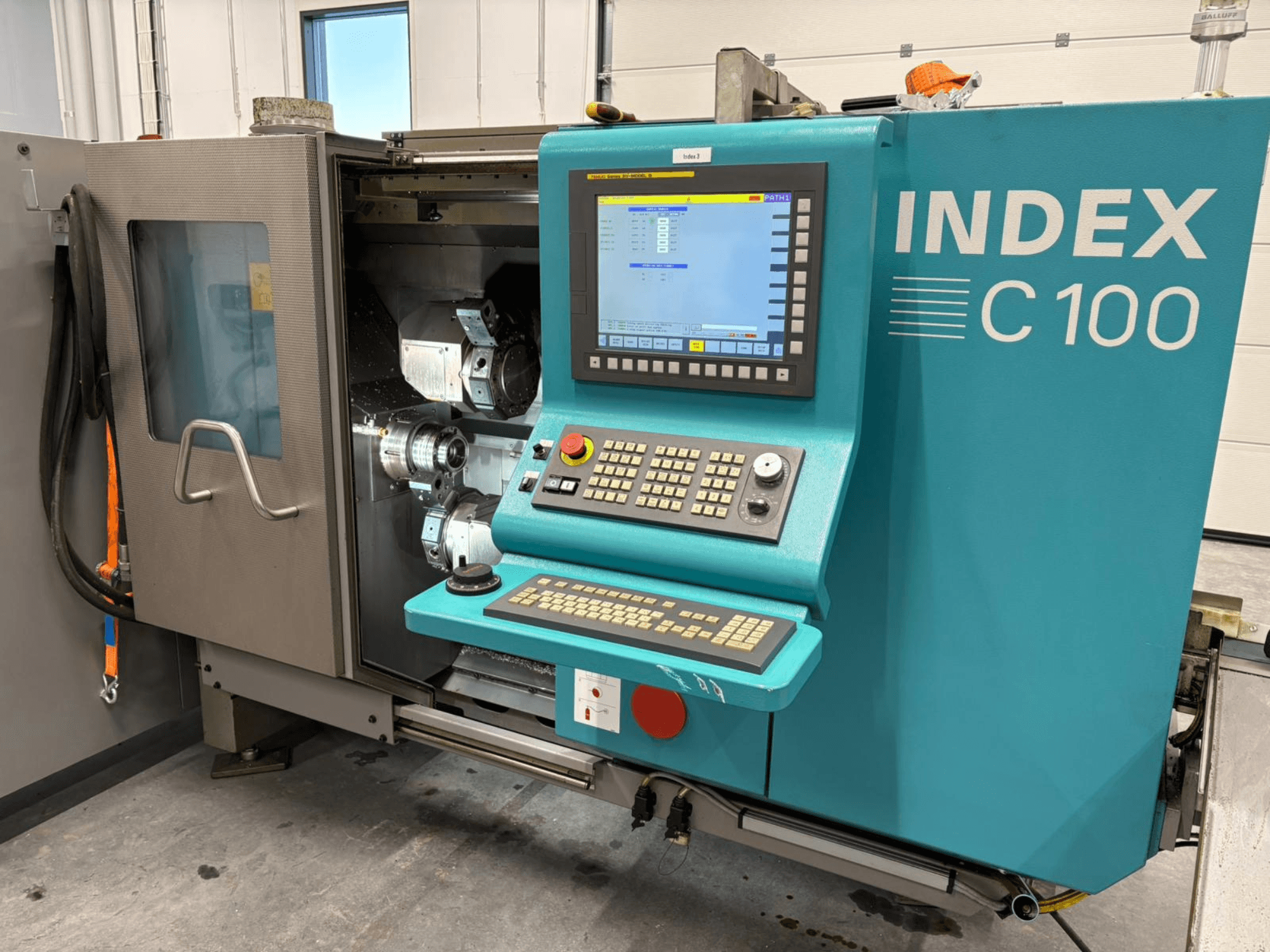 Front view of Index C100 Swiss Type Turning Machine with control panel and open enclosure displaying internal components.