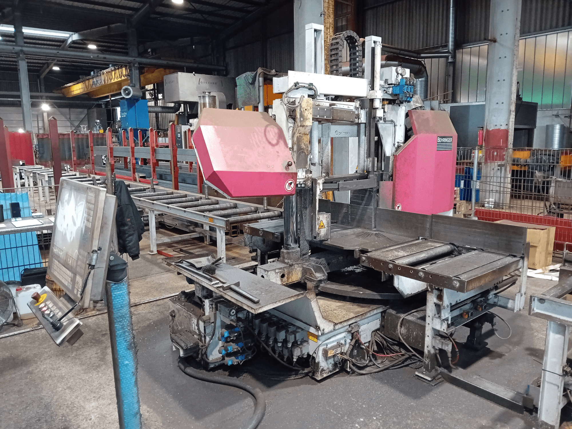 Behringer band saw machine in a factory, front view, featuring a large cutting blade and control panel with buttons.