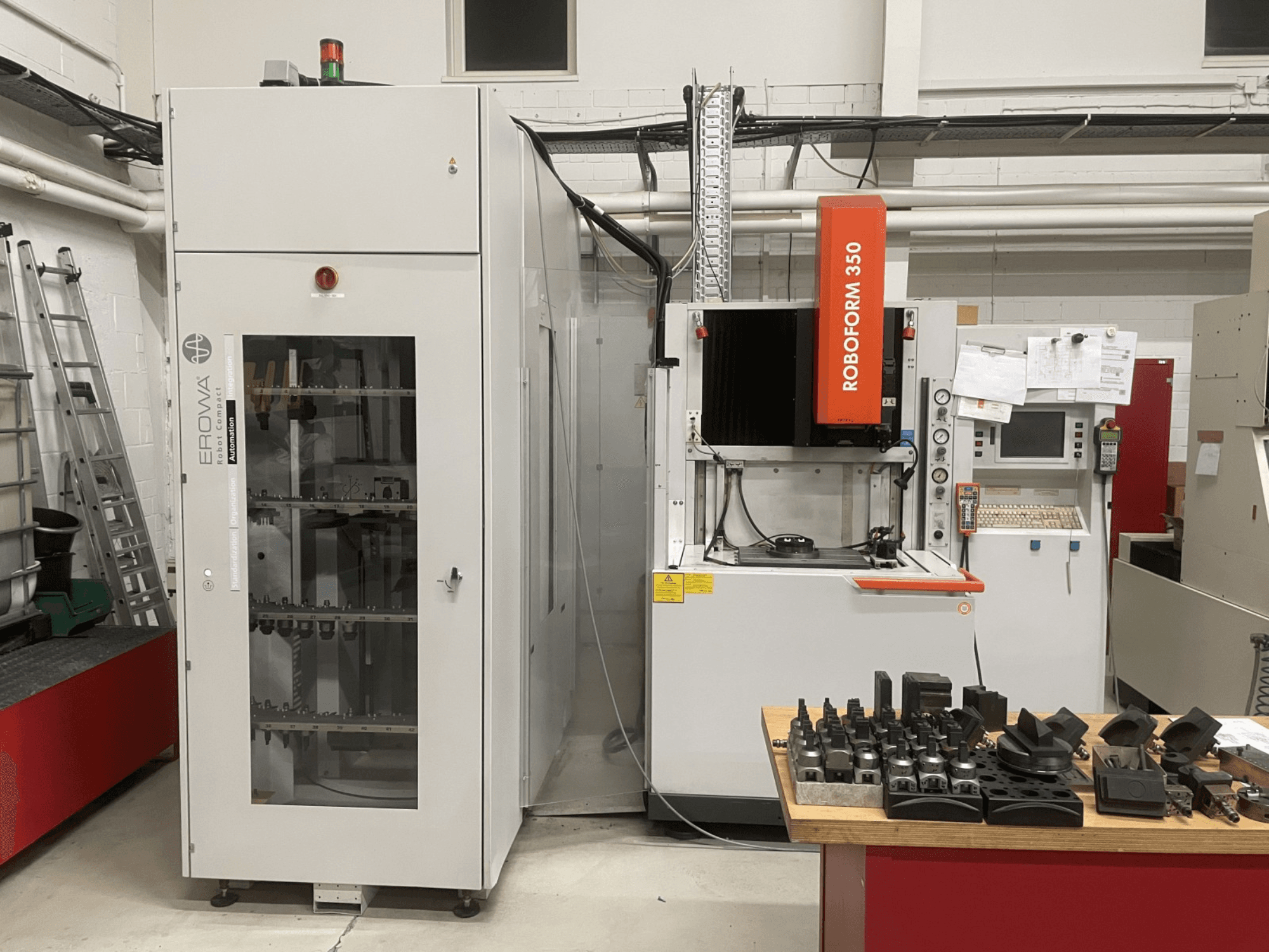 Die-sinking EDM machine CHARMILLES Roboform 350, front view, with tools displayed on a table and adjacent equipment.