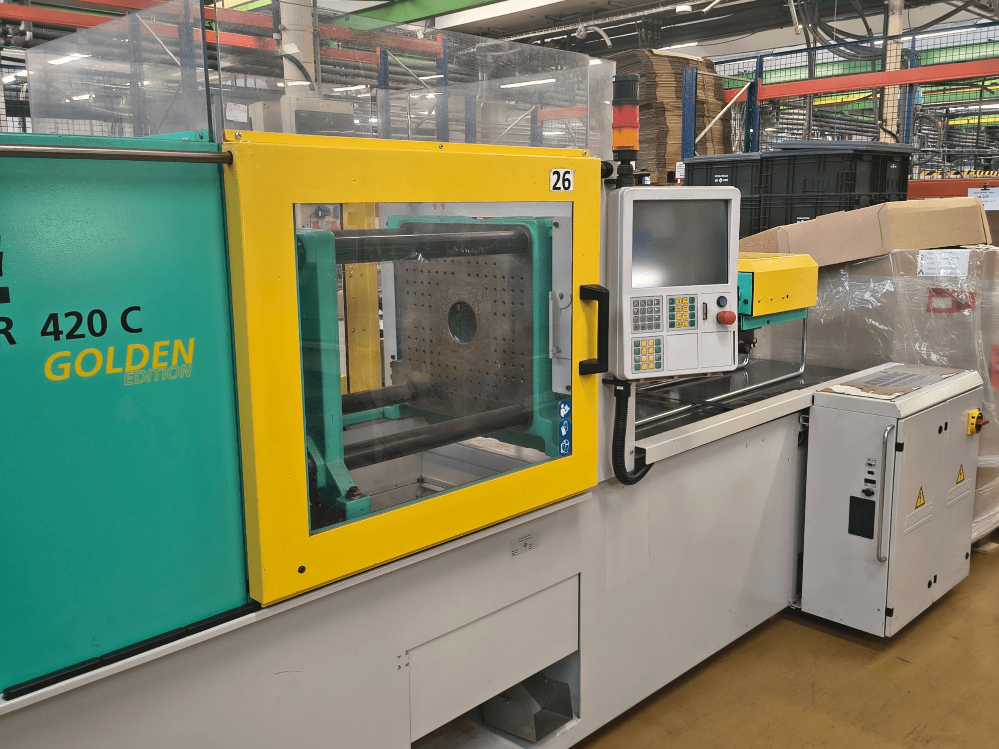 Injection molding machine, ARBURG 420 C Golden Edition, front view; features control panel, clear safety guard, and surrounding workspace.