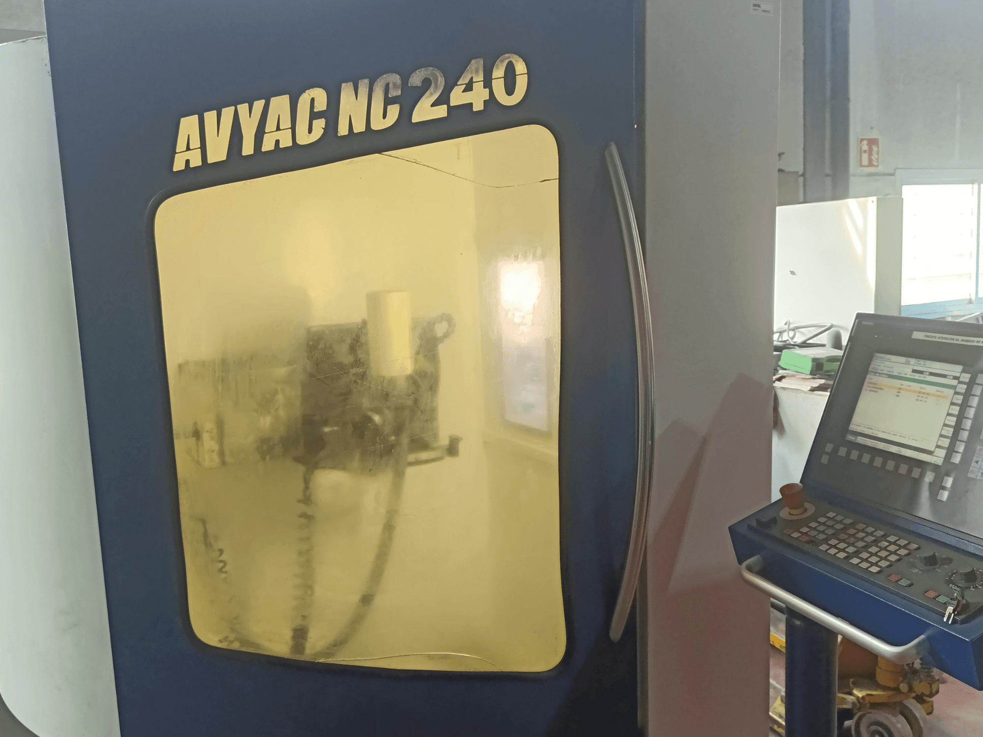 AVYAC NC240 cylindrical grinding machine, side view showing control panel and partially visible grinding area through the window.