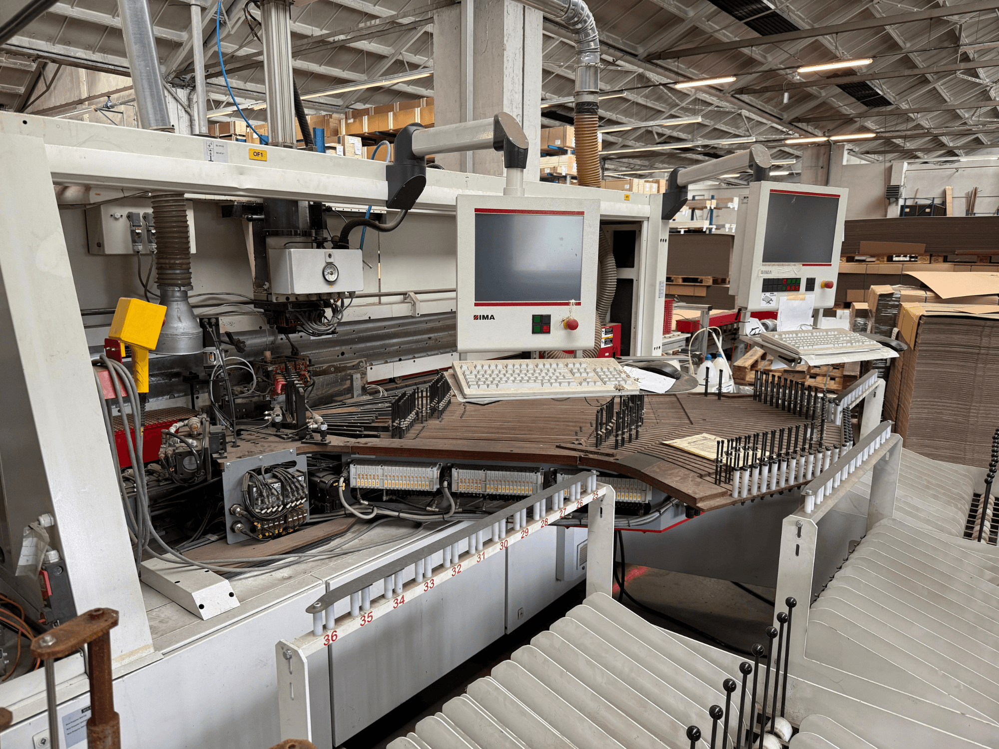 IMA precision woodworking machine with dual monitors and control panels, front view showing conveyor and tooling area.