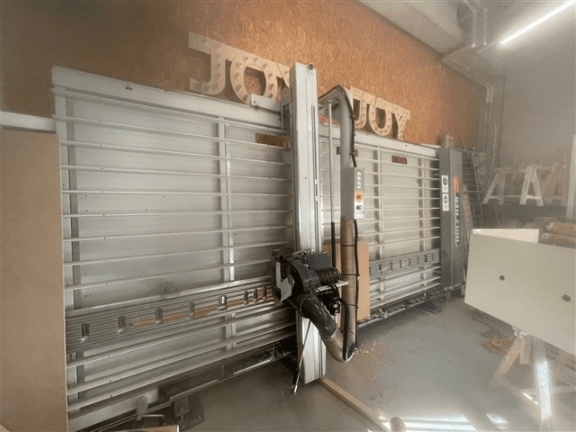 Horizontal panel saw, brand Holz-Her, side view, showcases saw blade, dust extraction, and storage space.