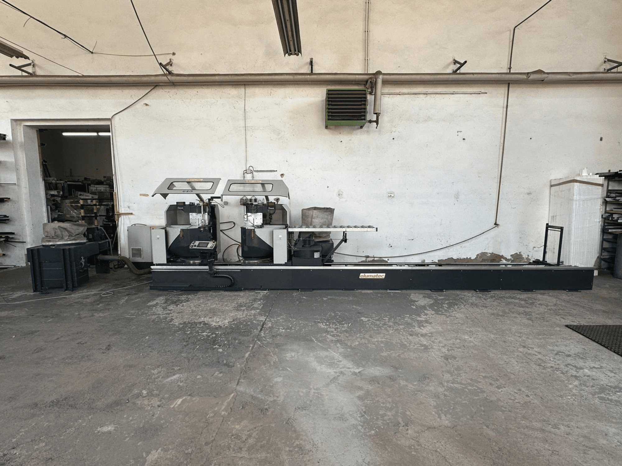 Elumatec DG 244 circular metal saw in a workshop, side view showing dual saws and operating controls on a sturdy base.