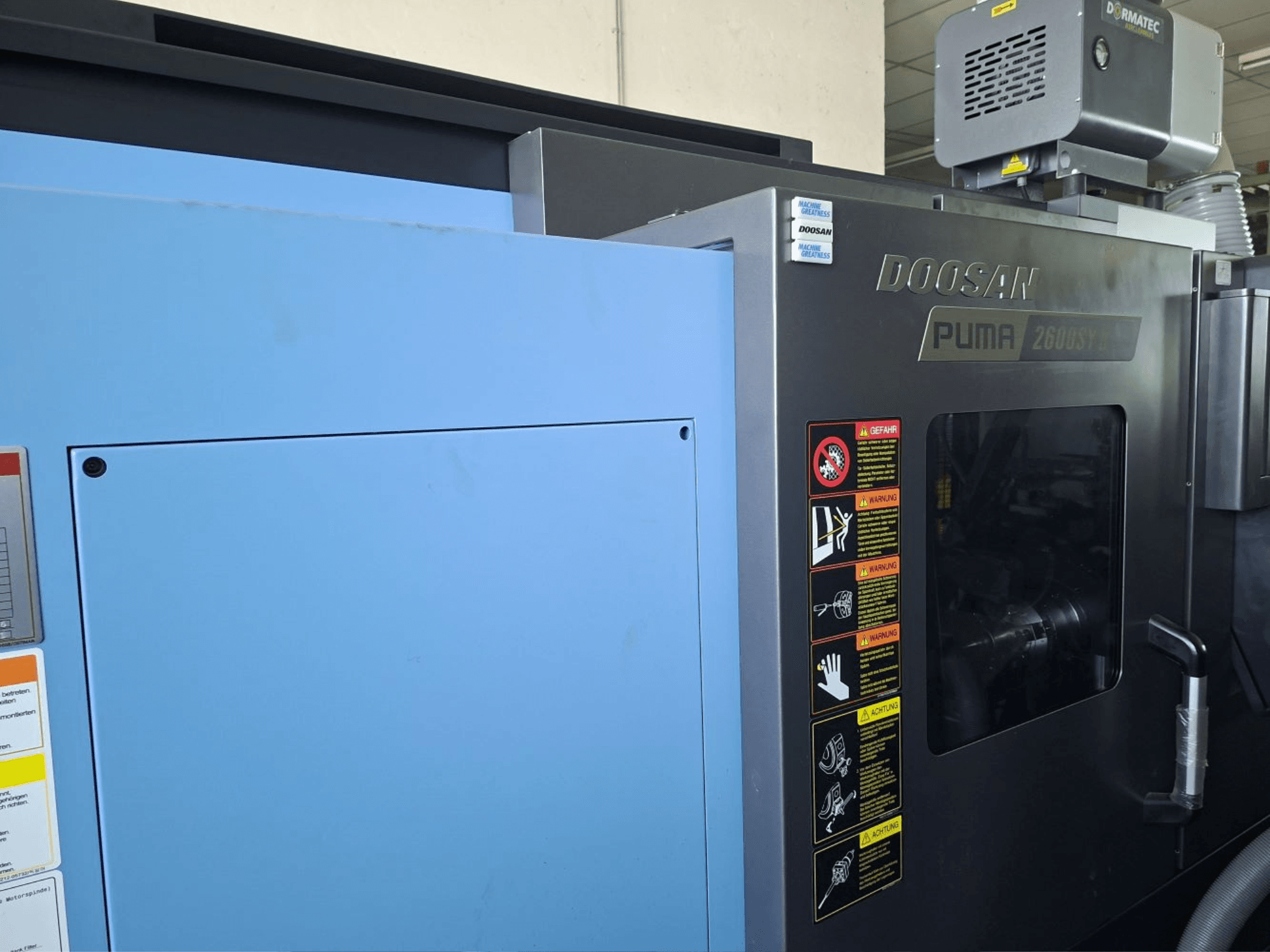 DOOSAN PUMA 2600 SY II horizontal turning machine, front view, showcasing safety labels and blue paneling.