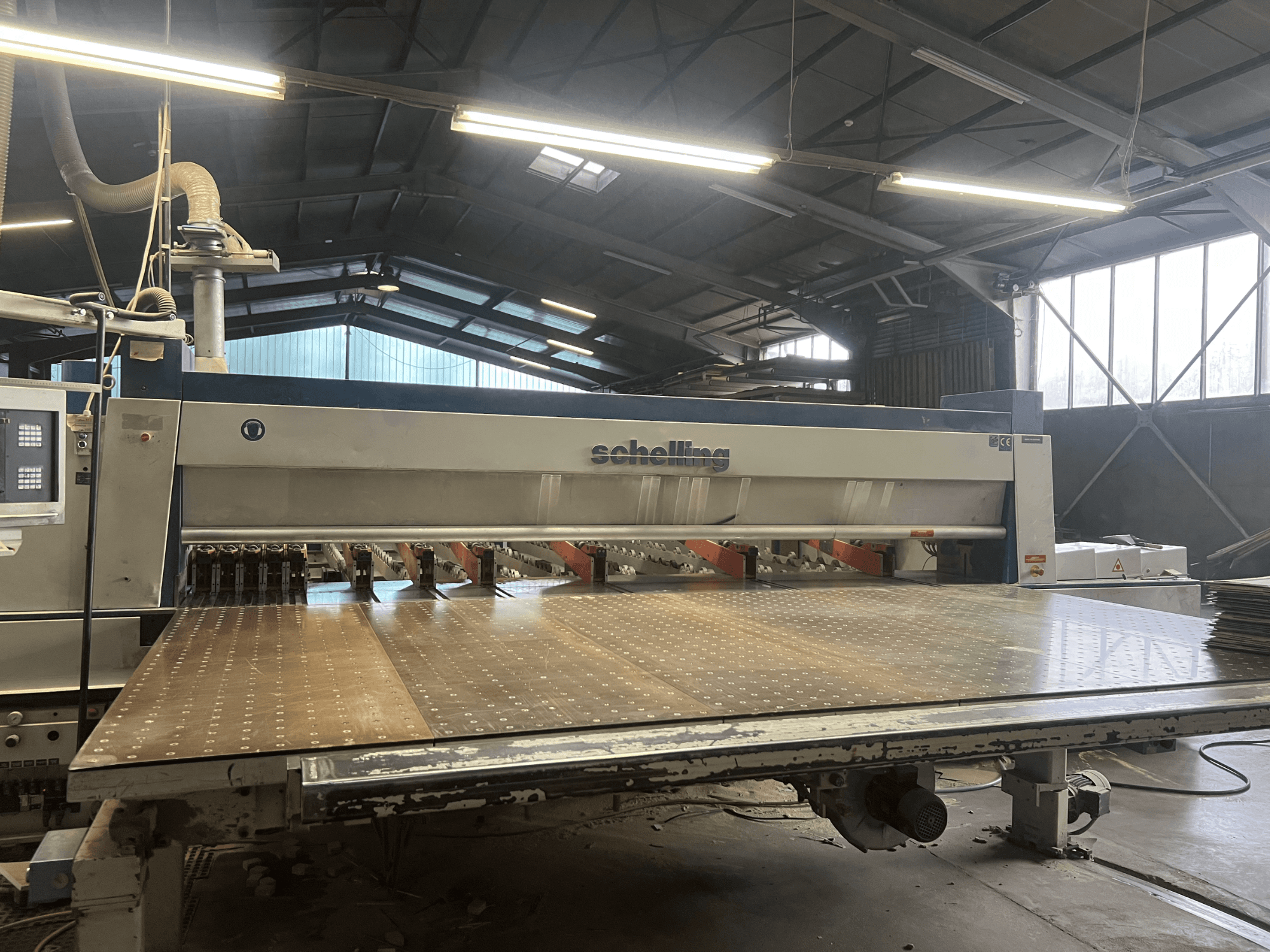 Schelling panel saw showing front view, with a large perforated cutting table and multiple blades for precise wood cutting.