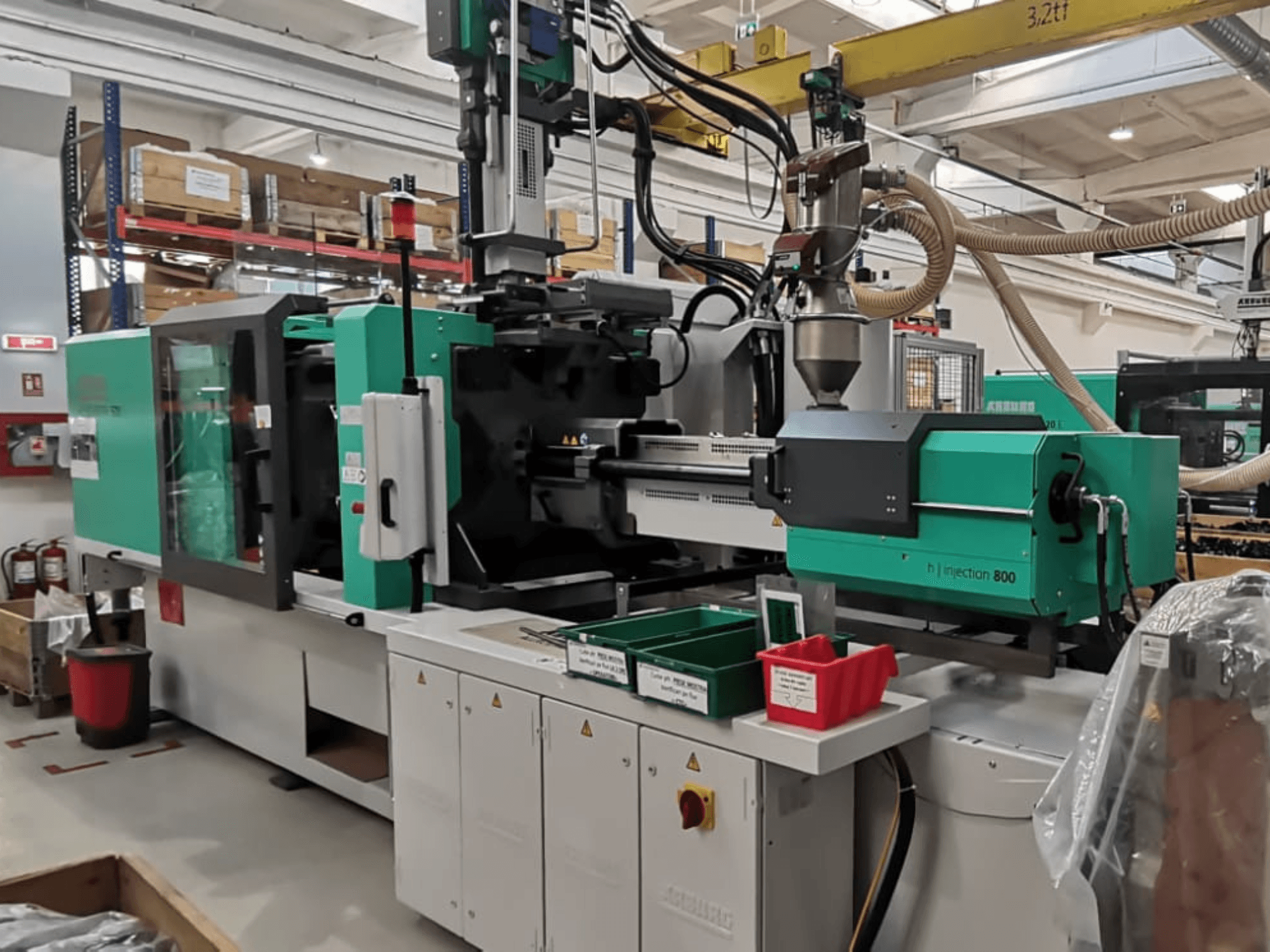 H injection 800 machine in a factory, front view, featuring a green and black design, with control panels and bins for parts.
