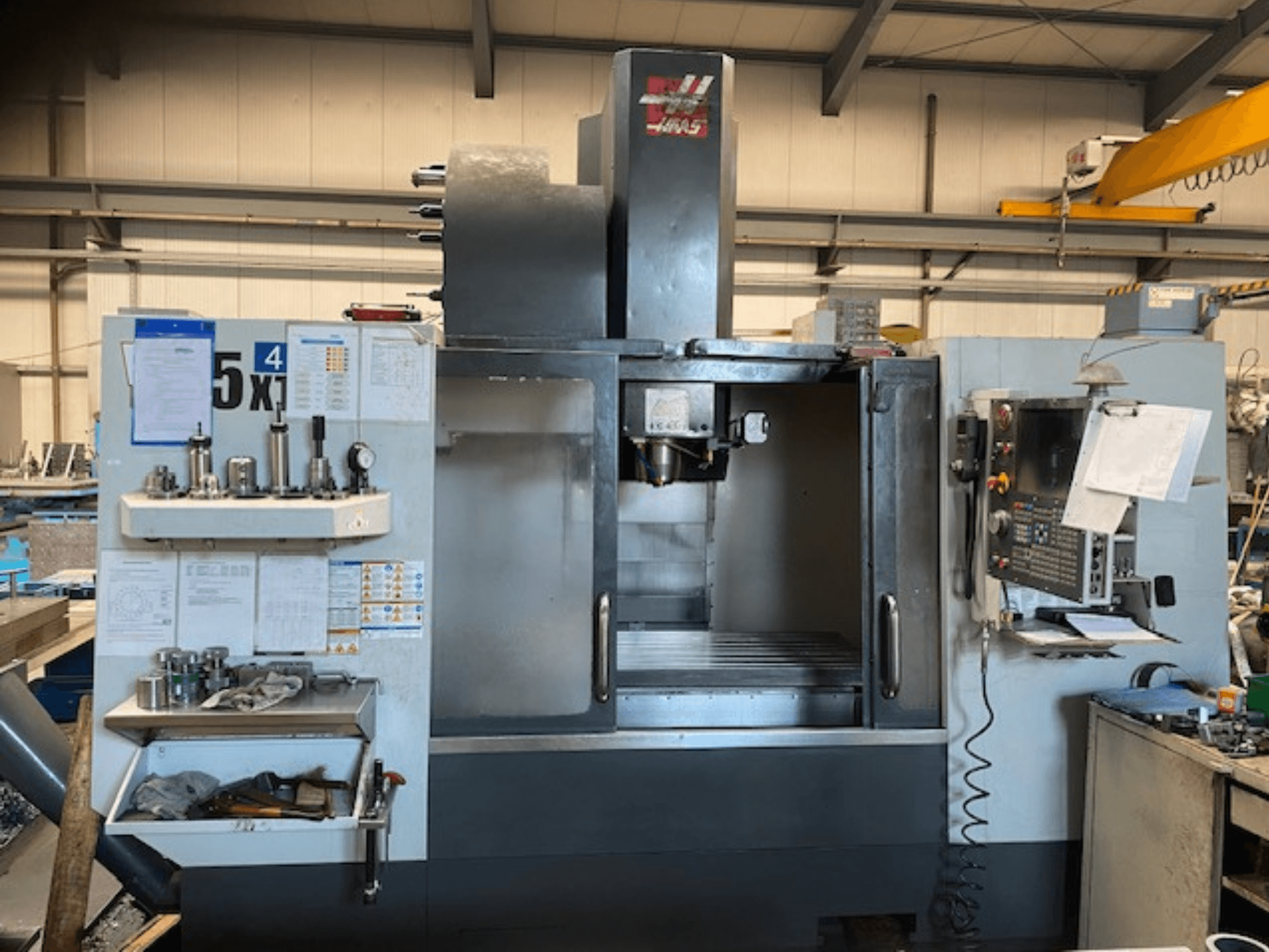 Haas VF-5 vertical machining center, front view, showcasing control panel, tool storage, and spindle area.