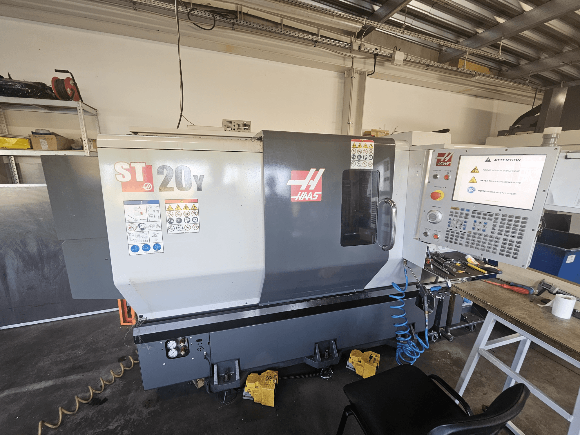 Haas ST-20Y CNC lathe, front view; includes control panel, safety warnings, and air hose attachment.