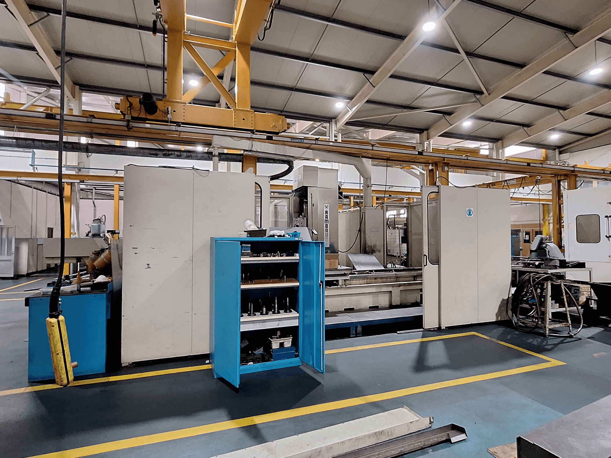 Gantry milling machine Rambaudi RX 1250, front view with tool storage, in a spacious industrial workspace.