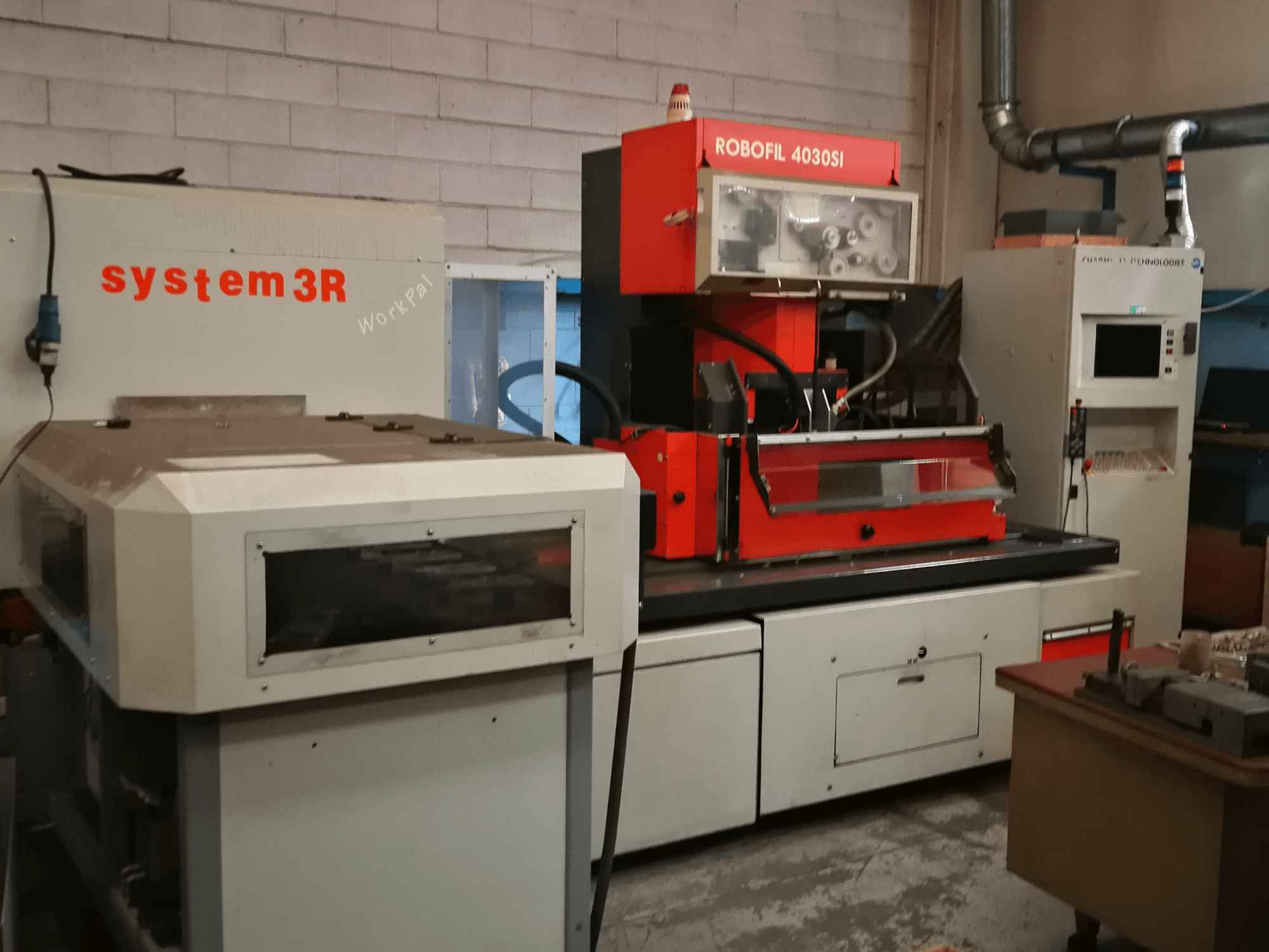 Front view of CHARMILLES ROBOFIL 4030 Si wire EDM machine, featuring a red and grey exterior and adjacent system3R workstation.