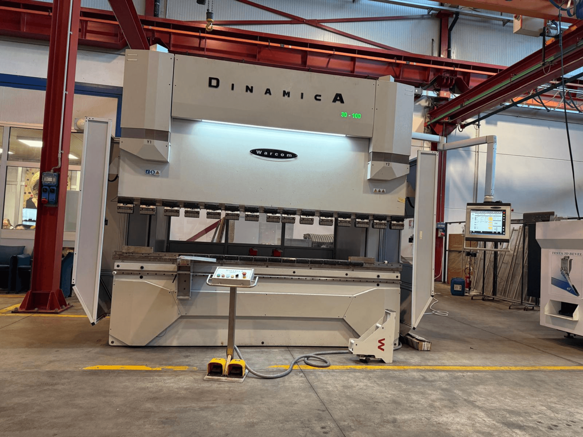 Dinamica Warcom hydraulic press brake, front view. Features control panel and multiple tooling stations for precision bending.