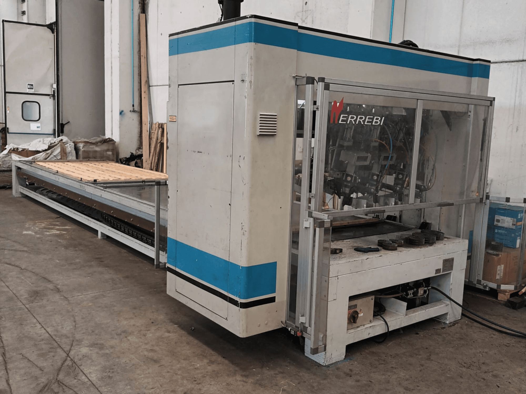 ERREBI machinery, side view, features a large processing table with mechanical components and transparent protective cover.