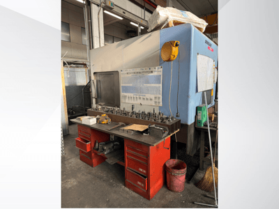 Doosan machining center with a red workbench and storage, displaying tools and equipment, viewed from the front.