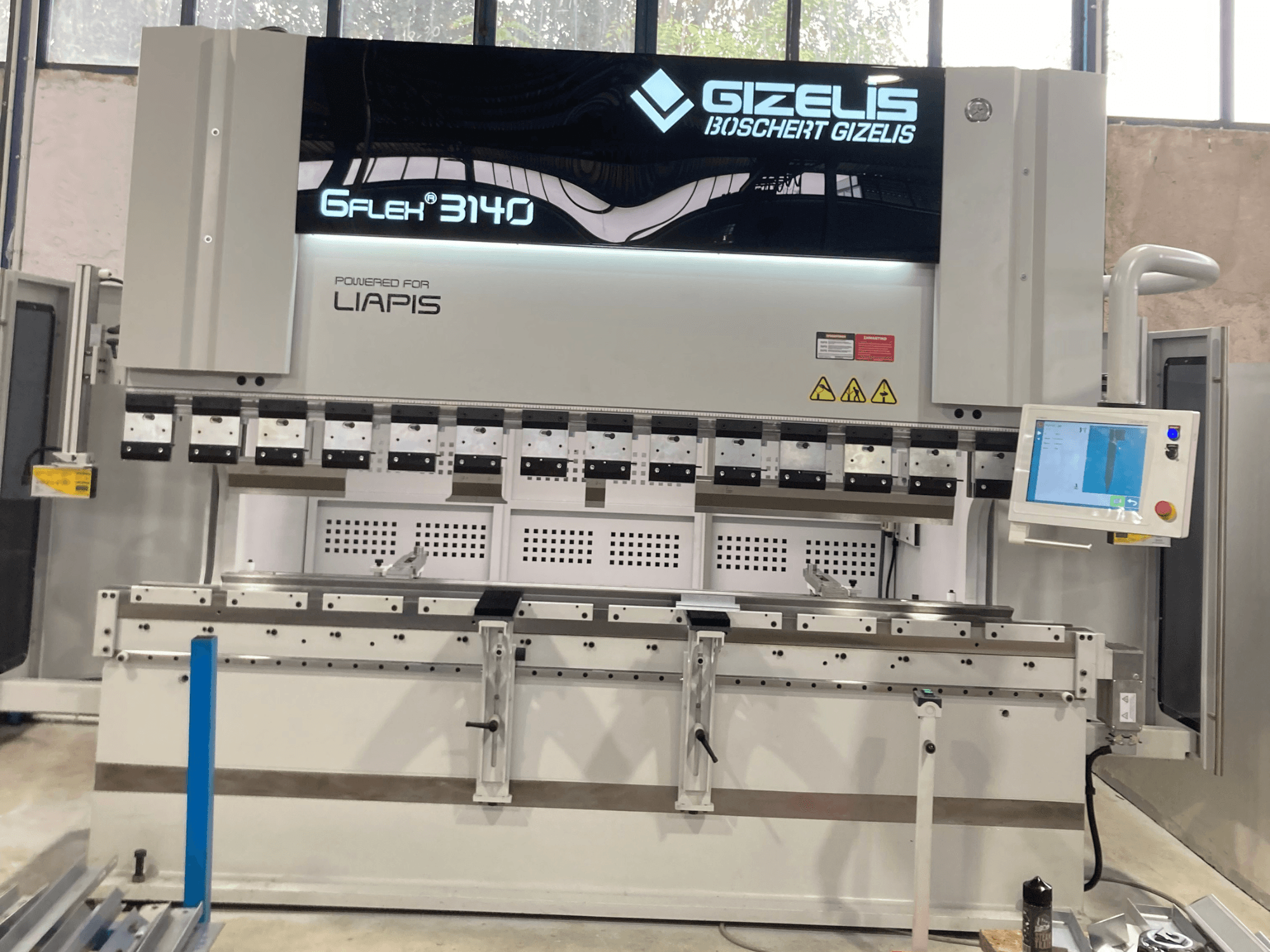Hydraulic press GIZELIS G-FLEX 3140 in front view with control screen, featuring multiple bending tools and safety labels.