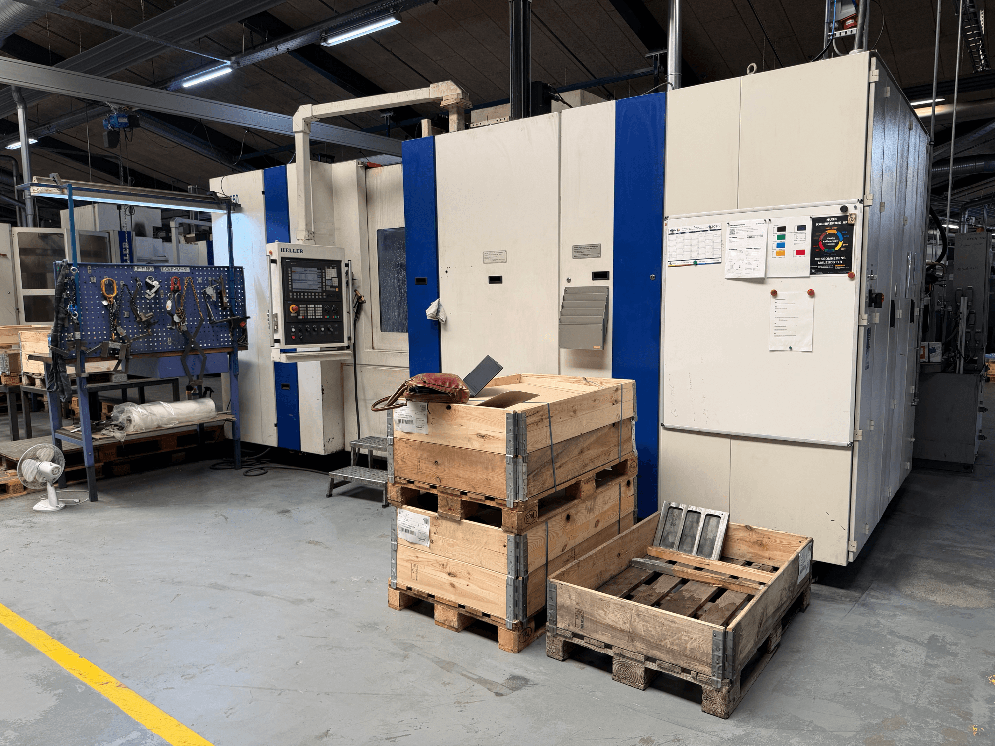 HORIZONTAL MACHINING CENTRE HELLER MCH 250 in workshop, side view with wooden pallets and tool rack visible.