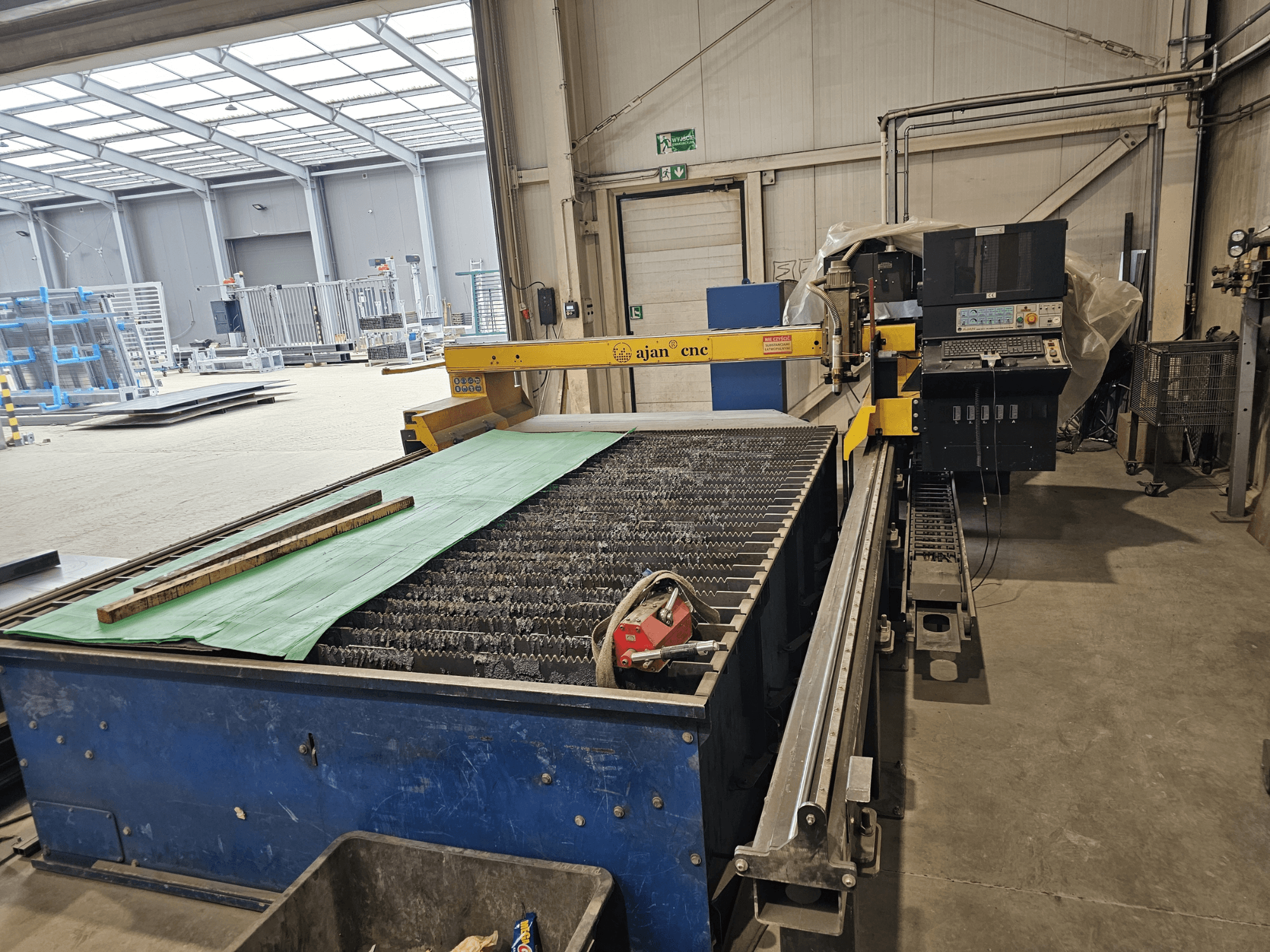 AJAN PP16011 Auto plasma cutting machine in side view, featuring a cutting table and control panel, set in a workshop environment.