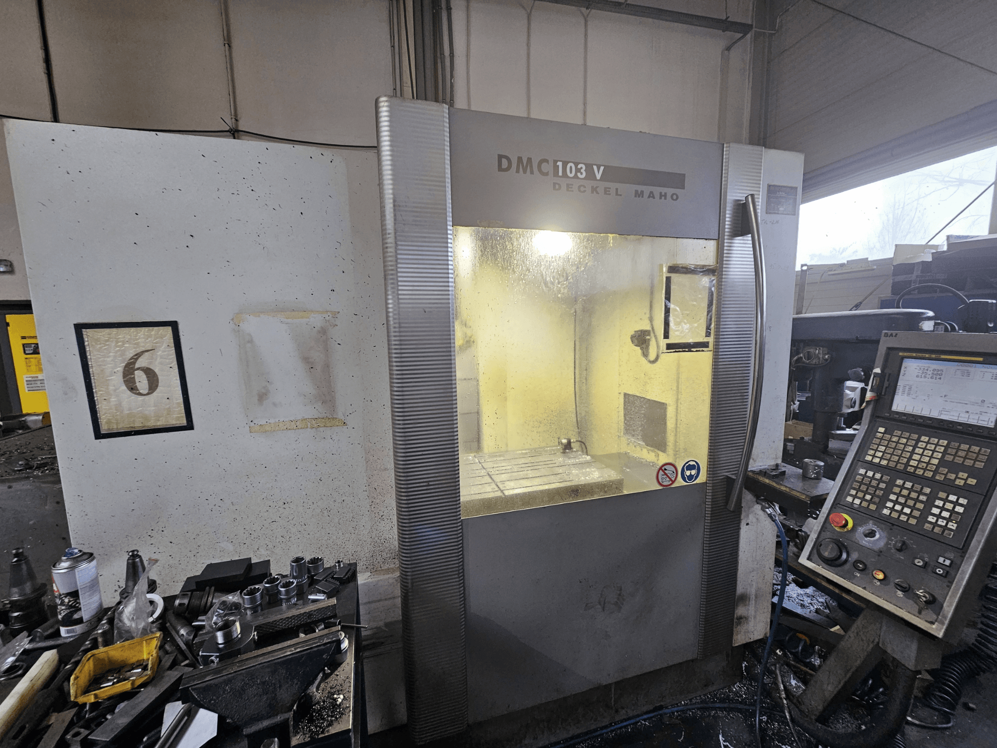 Deckel Maho DMC 103 V CNC machine, front view, with control panel and workspace, featuring a number '6' on the wall.