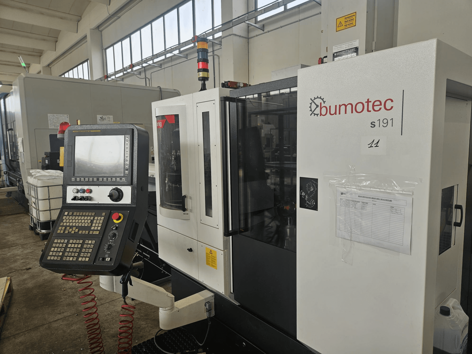 Bumotec s191 Turn-Mill Centre front view, featuring a control panel and operational labels in a factory setting.