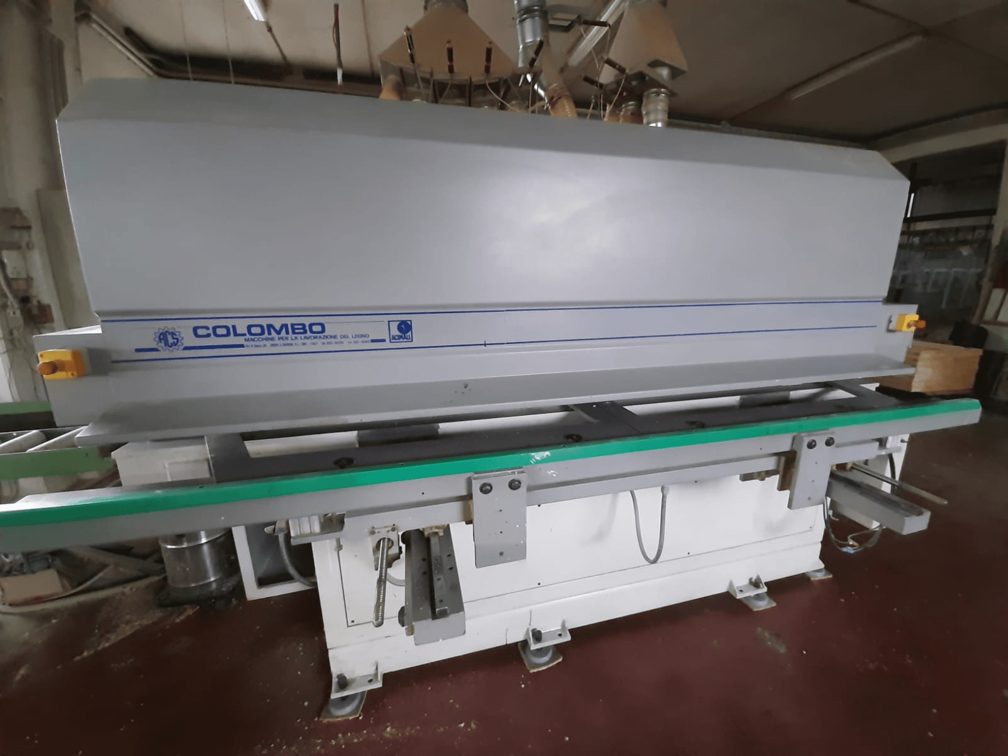 Colombo wood processing machine, front view, featuring a long green table, control buttons, and a gray body with blue accents.