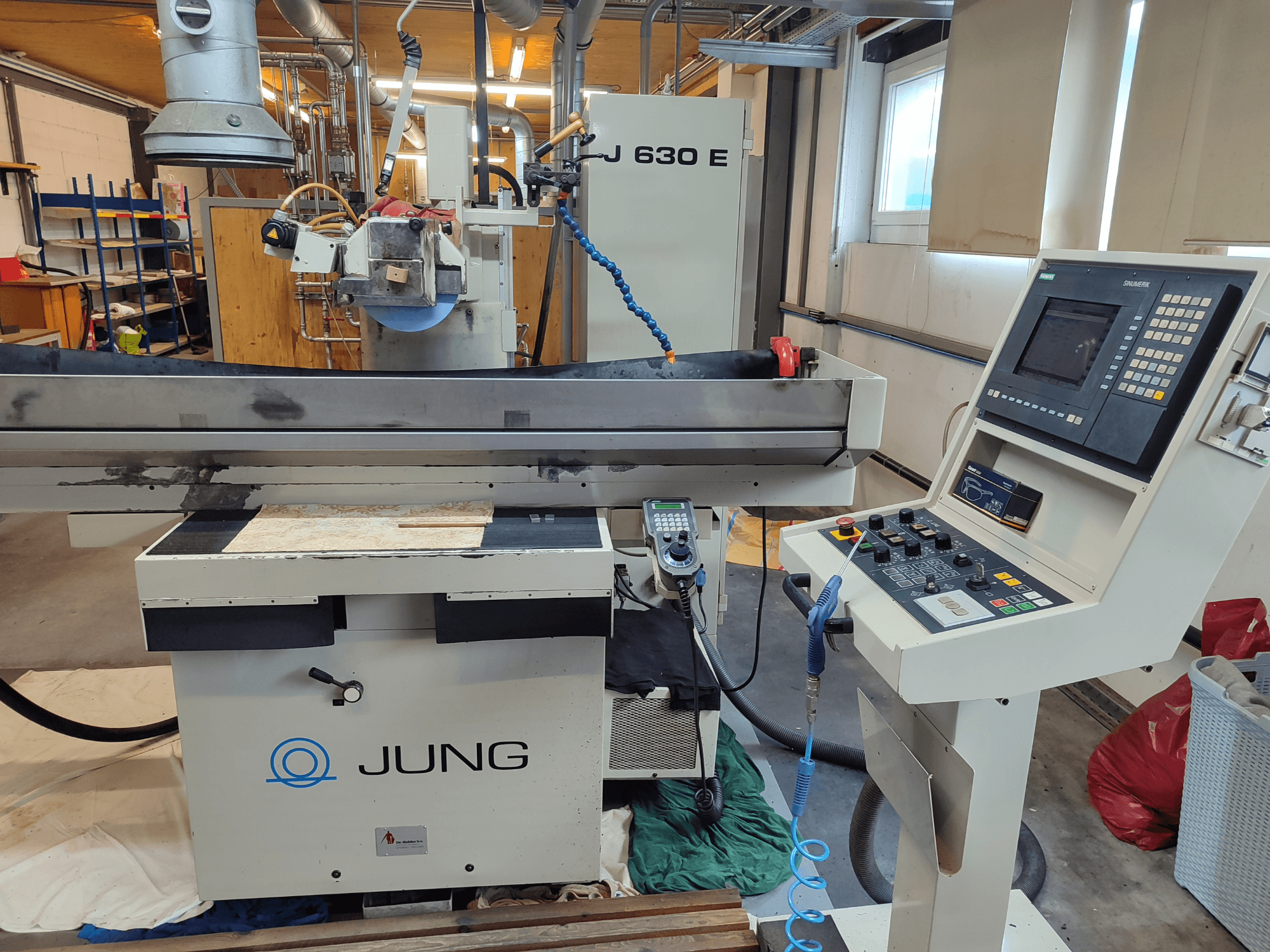 Front view of the JUNG J 630 E surface grinding machine, showcasing the grinding wheel, control panel, and work surface.