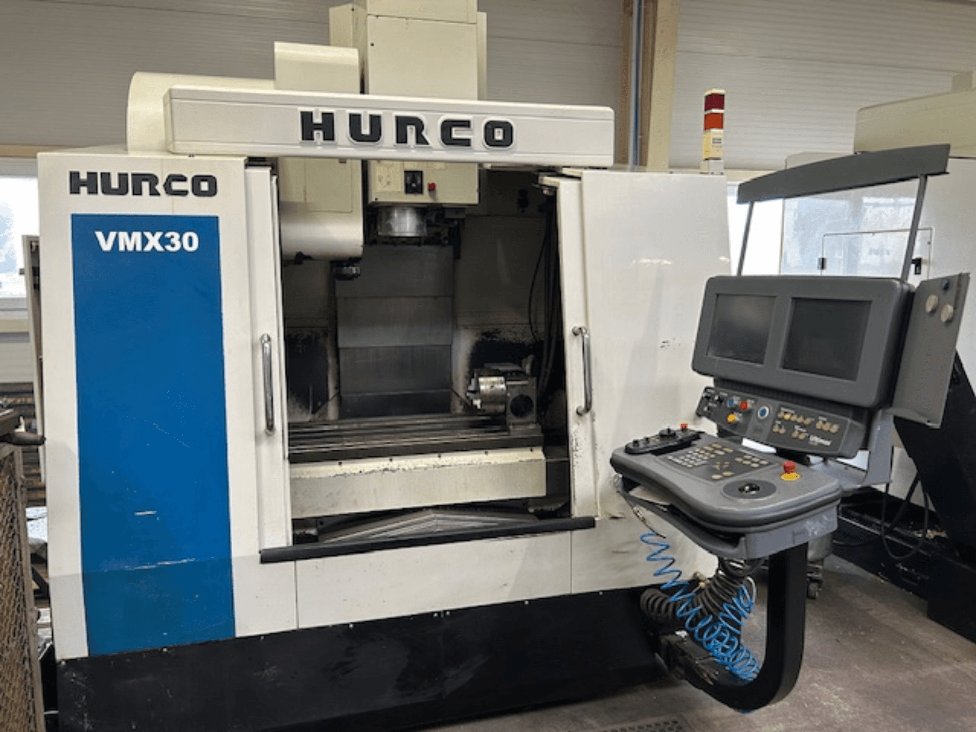 Hurco VMX30 CNC milling machine in a workshop, front view; features control panel with dual screens and operational buttons.