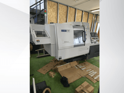 Citizen M16VIII CNC lathe in front view, features control panel and safety alert lights, placed on green flooring.