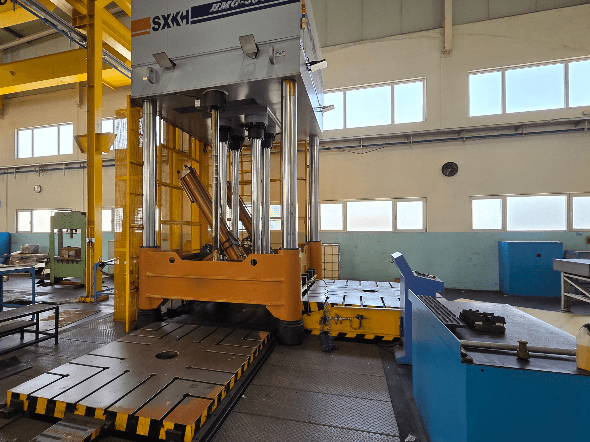 Hydraulic press SXKH HMG-300JM front view, featuring large pressing cylinders and a robust base in a factory setting.