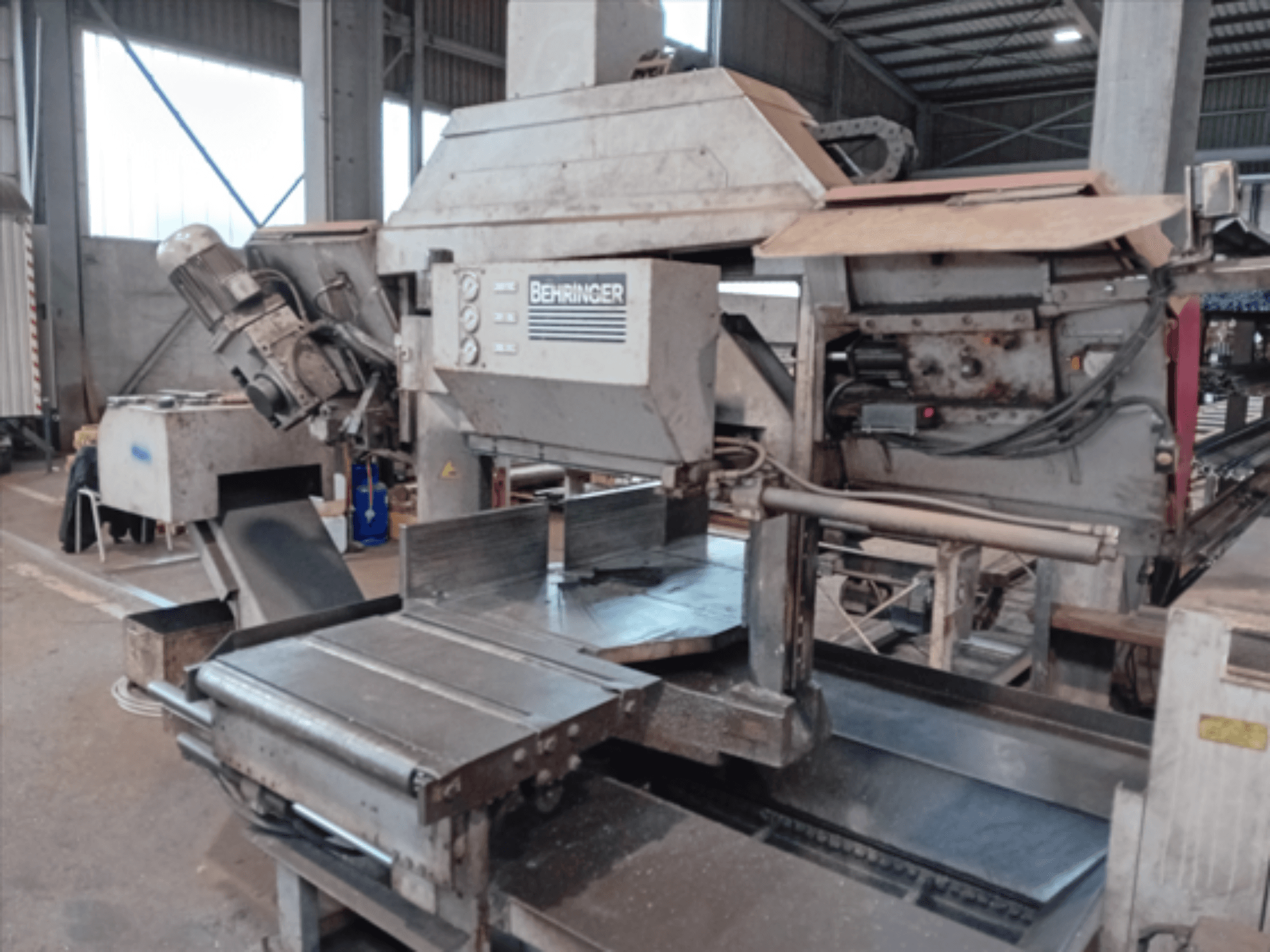 Behringer band saw, front view, features a large blade, motor, and adjustable table, ideal for metal cutting in a workshop.