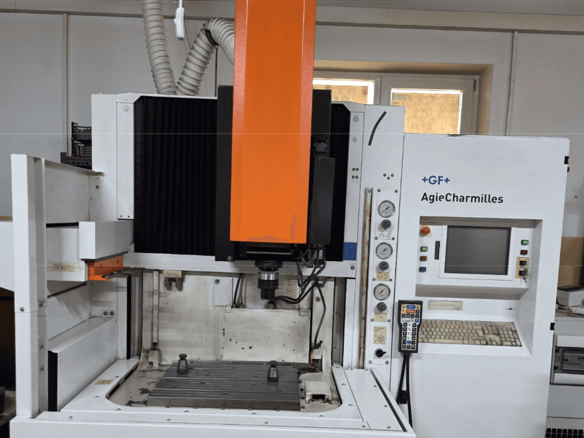 AgieCharmilles machining center in front view with a large orange spindle, control panel, and visible work table.