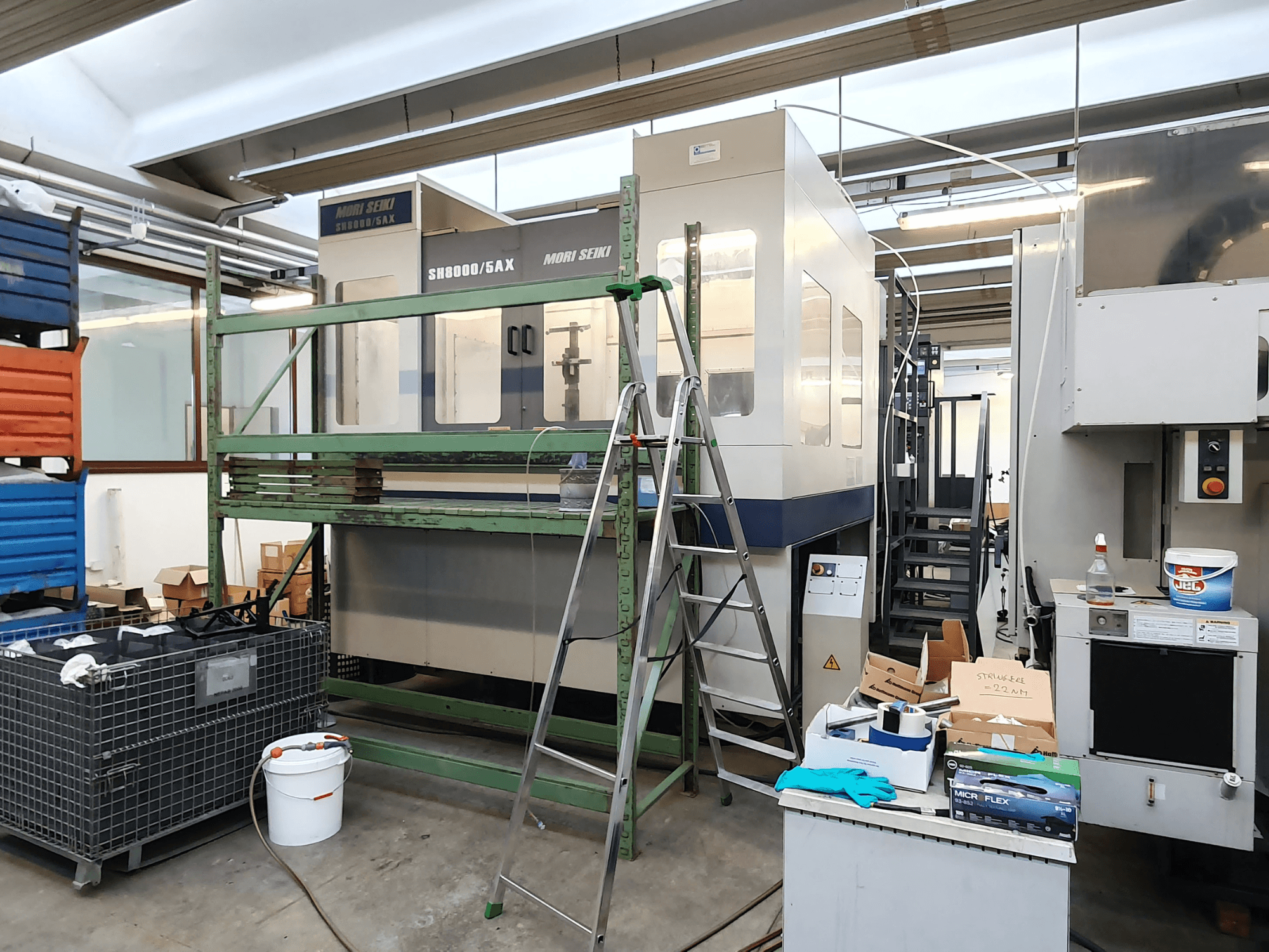 Mori Seiki SH-8000/5AX CNC machine in a workshop, front view, with workshop tools and storage boxes nearby.