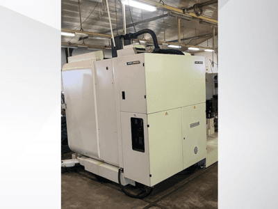 White industrial CNC machine viewed from the front, featuring control panel and ventilation, in a workshop setting.