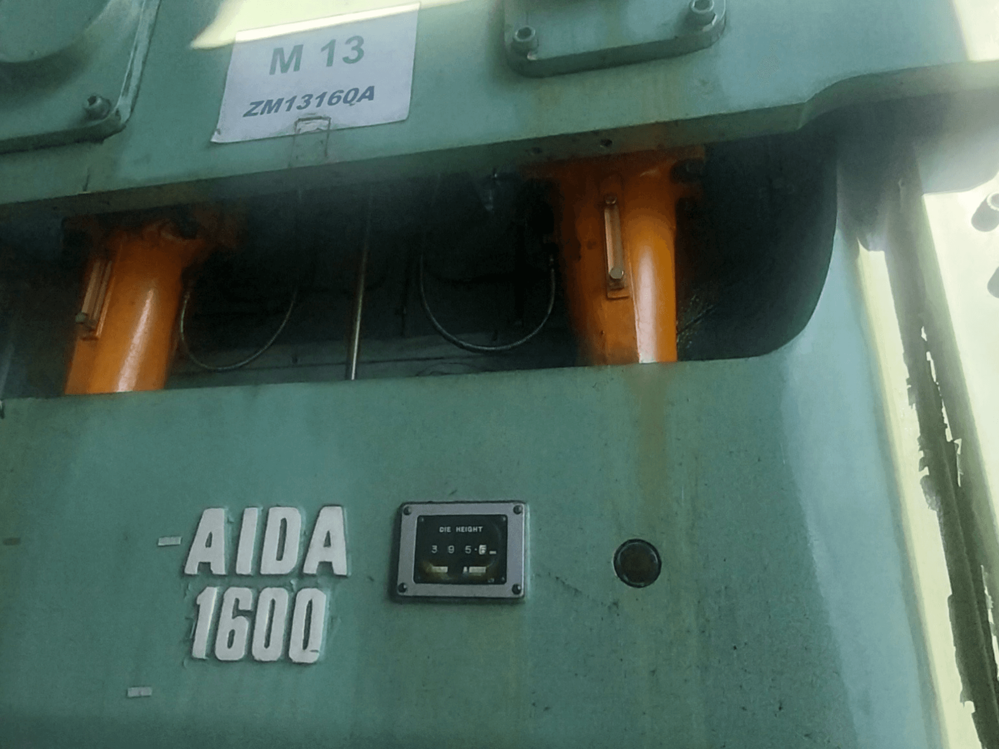 AIDA NC2-1600 mechanical stamping press, front view; orange hydraulic components and die height gauge visible.