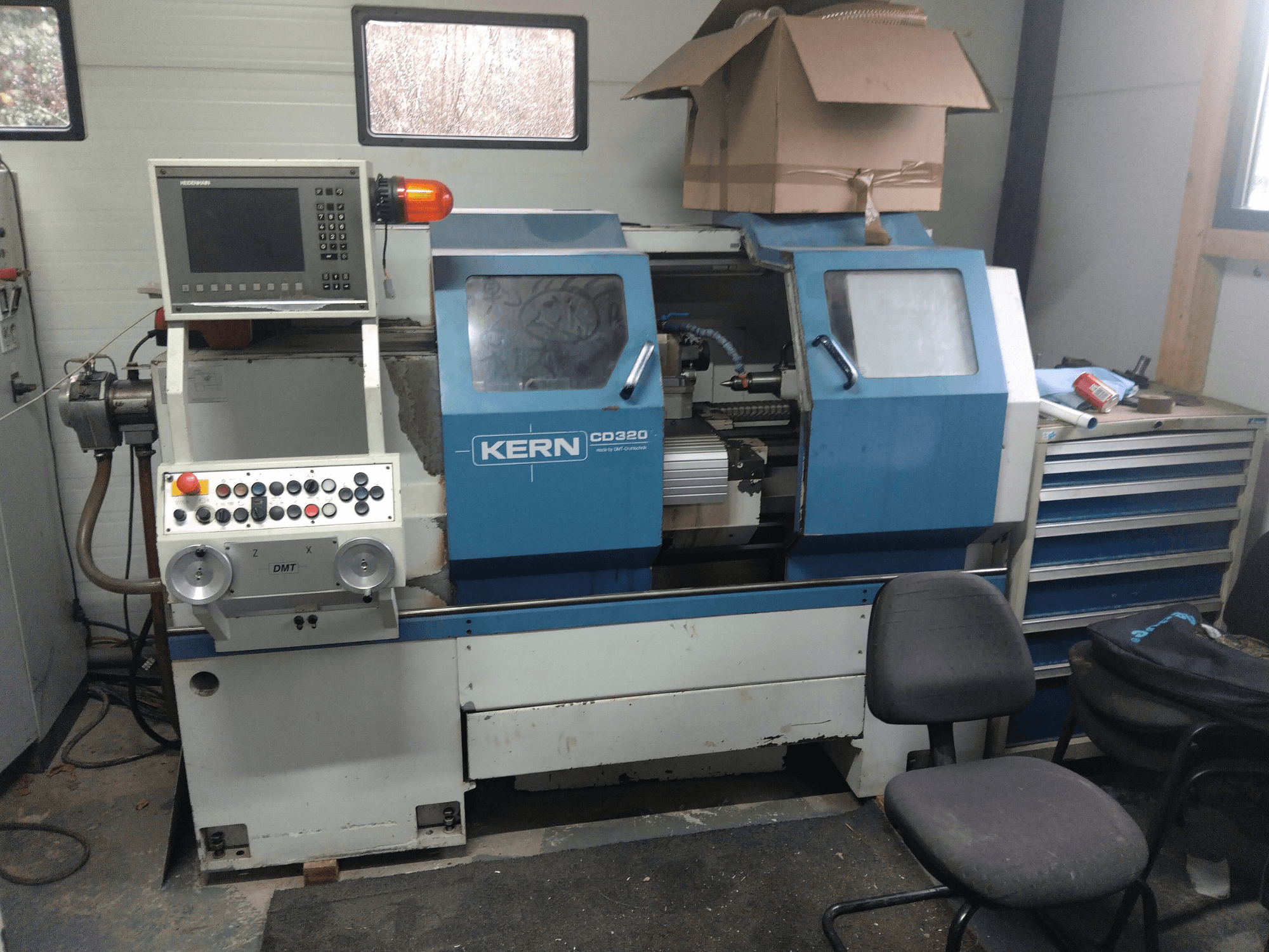 KERN CD320 milling machine, front view with control panel, emergency button, and safety light visible beside tools and chairs.